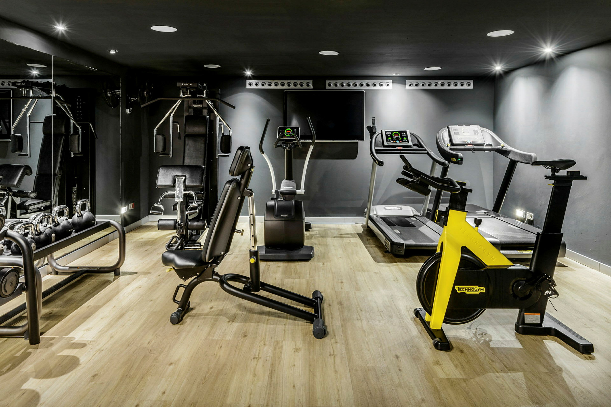 Fitnessrum med træningsmaskiner, inklusive løbebånd, cykel og fitnessudstyr. (AI-genereret tekst)