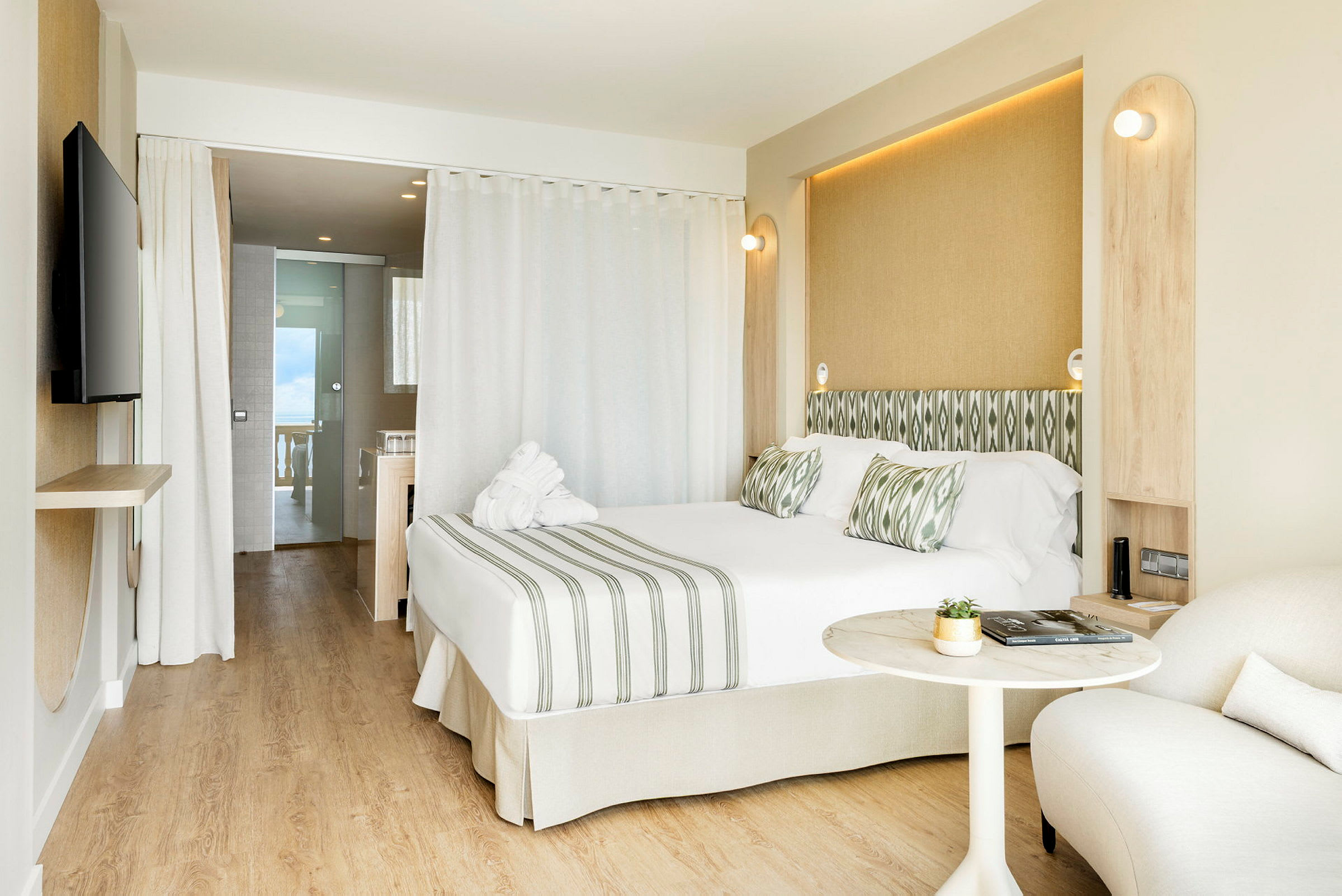 Billede af et moderne hotelværelse med dobbeltseng, siddeområde og åbning mod badeværelse. (AI-genereret tekst)