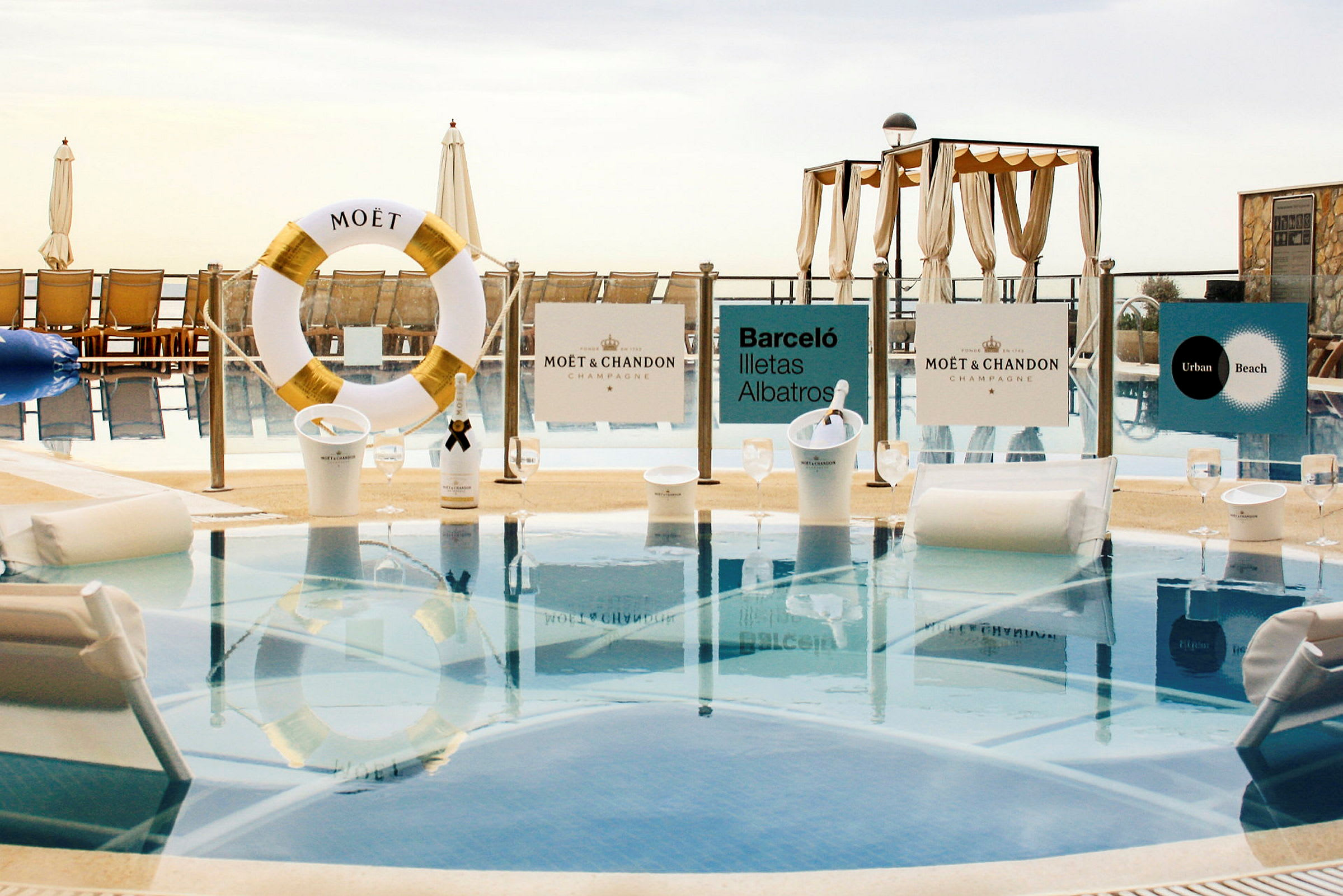 Billede af en luksuriøs swimmingpool med Moët & Chandon-skilte, liggestole og parasoller. (AI-genereret tekst)