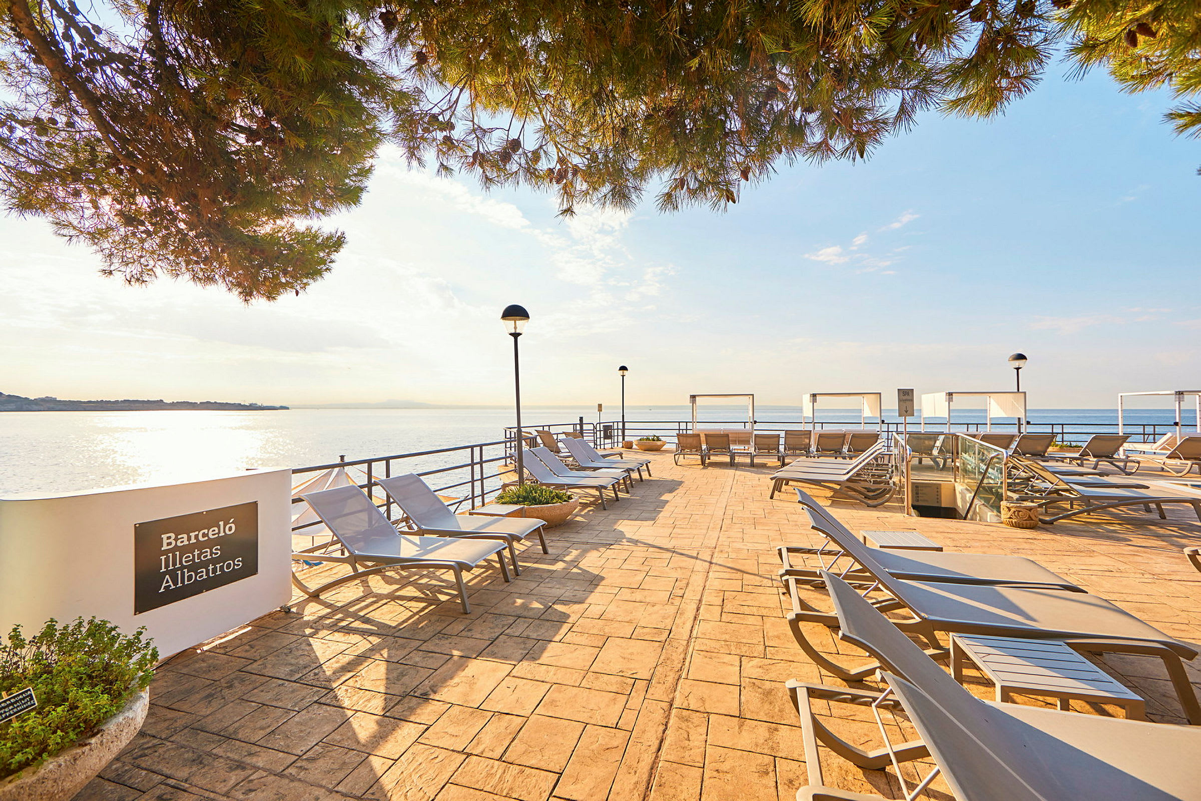 En udendørs terrasse med solvogne og udsigt over havet. (AI-genereret tekst)