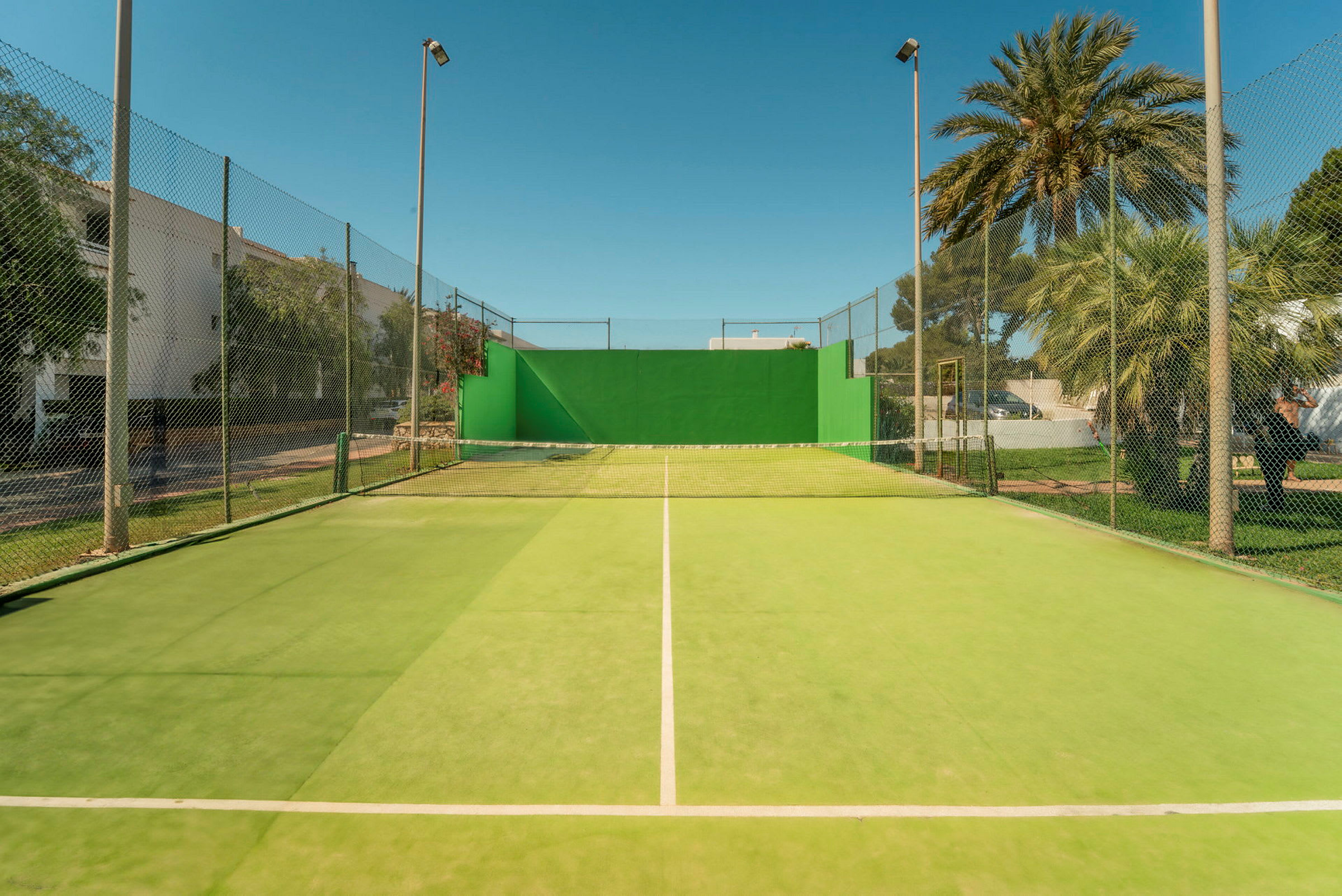 Tennisbane med grønt underlag og net. (AI-genereret tekst)