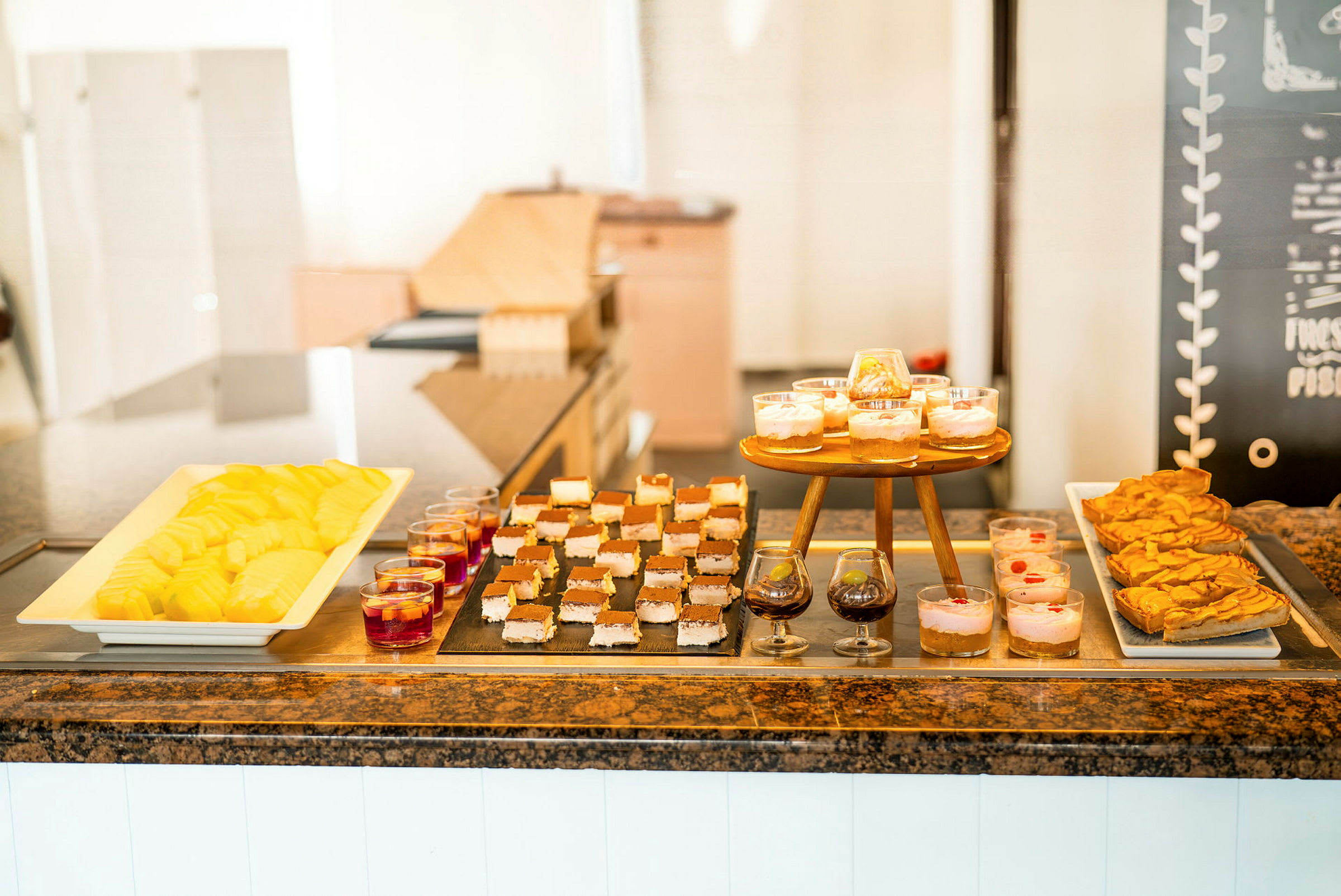 Buffet med forskellige desserter såsom udskåret frugt, bagværk og dessert i glas. (AI-genereret tekst)