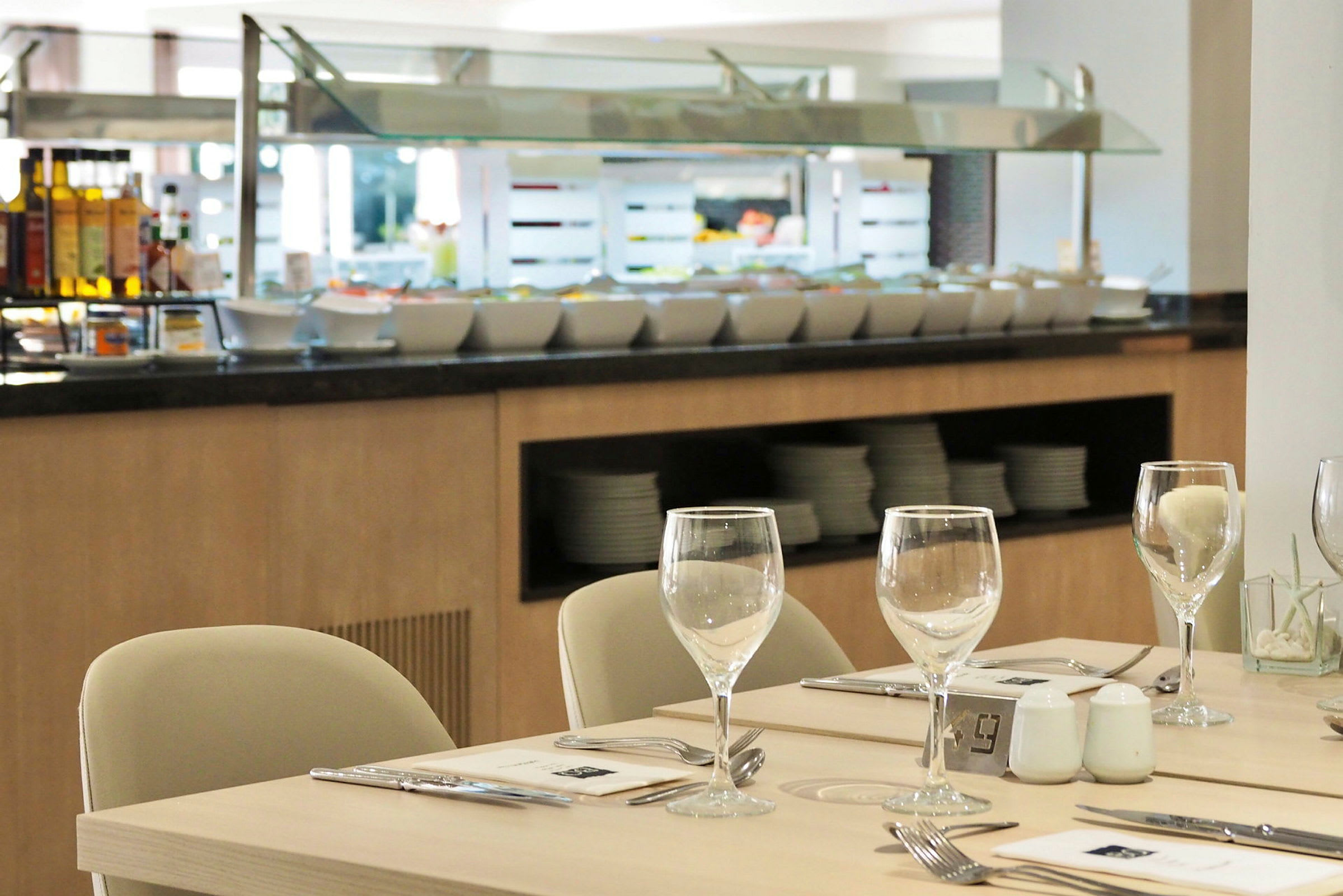 En restaurantbuffet med siddepladser og dækkede borde i forgrunden. (AI-genereret tekst)