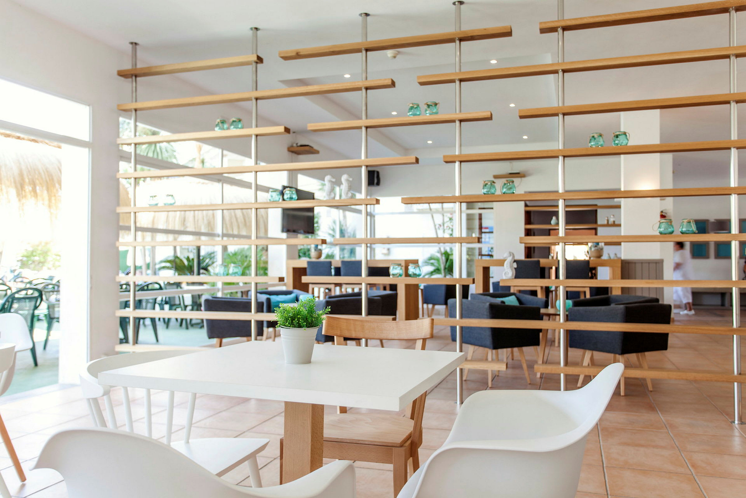 En lys og moderne restaurant med hvide borde, træstole og dekorative hylder. (AI-genereret tekst)