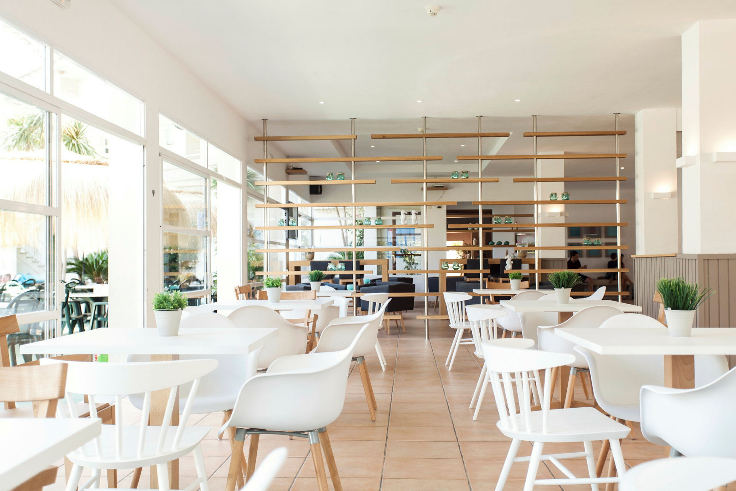 Lys og moderne restaurant med hvide møbler og grønne planter. (AI-genereret tekst)