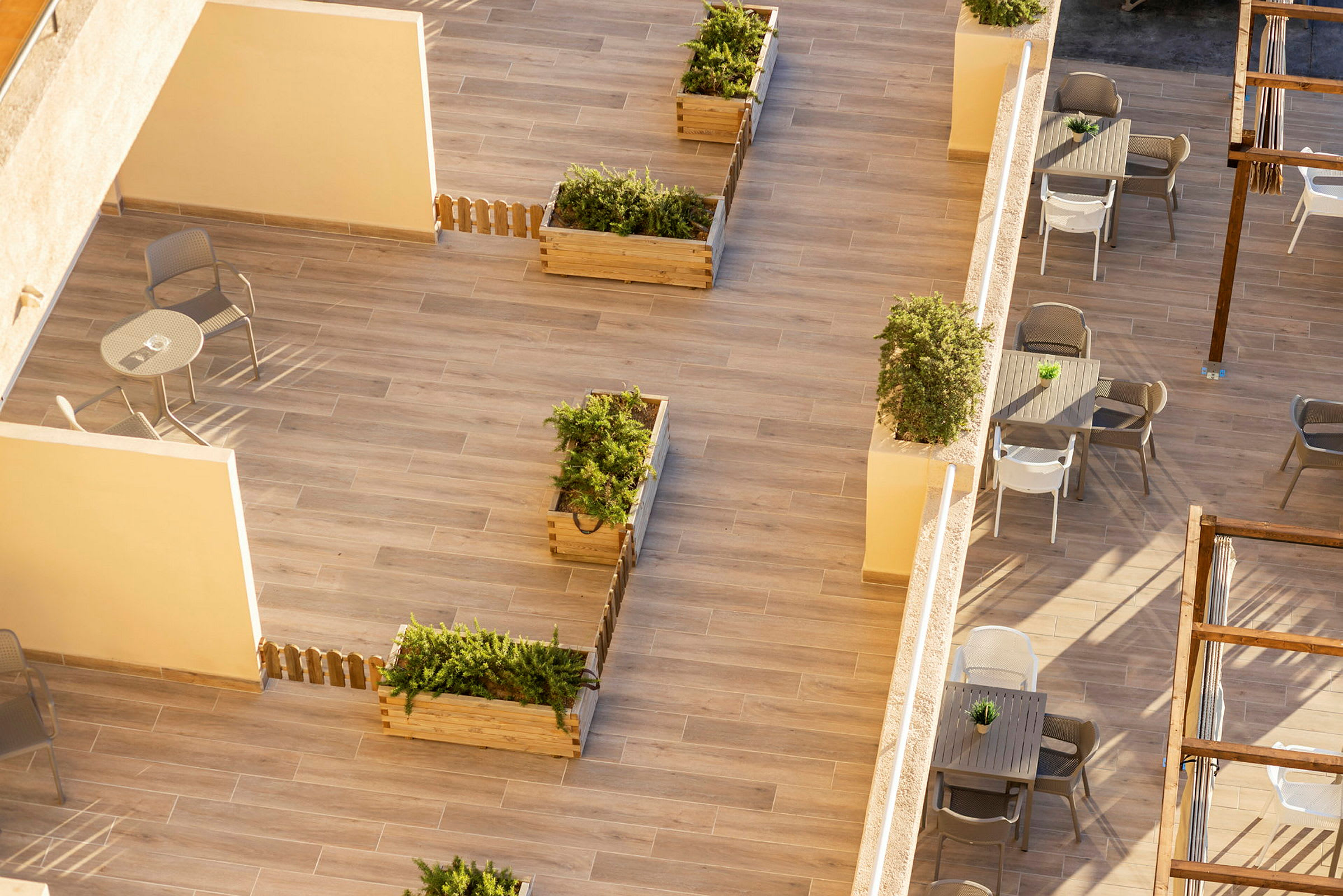Udsigt over en terrasse med plantekasser, borde og stole. (AI-genereret tekst)