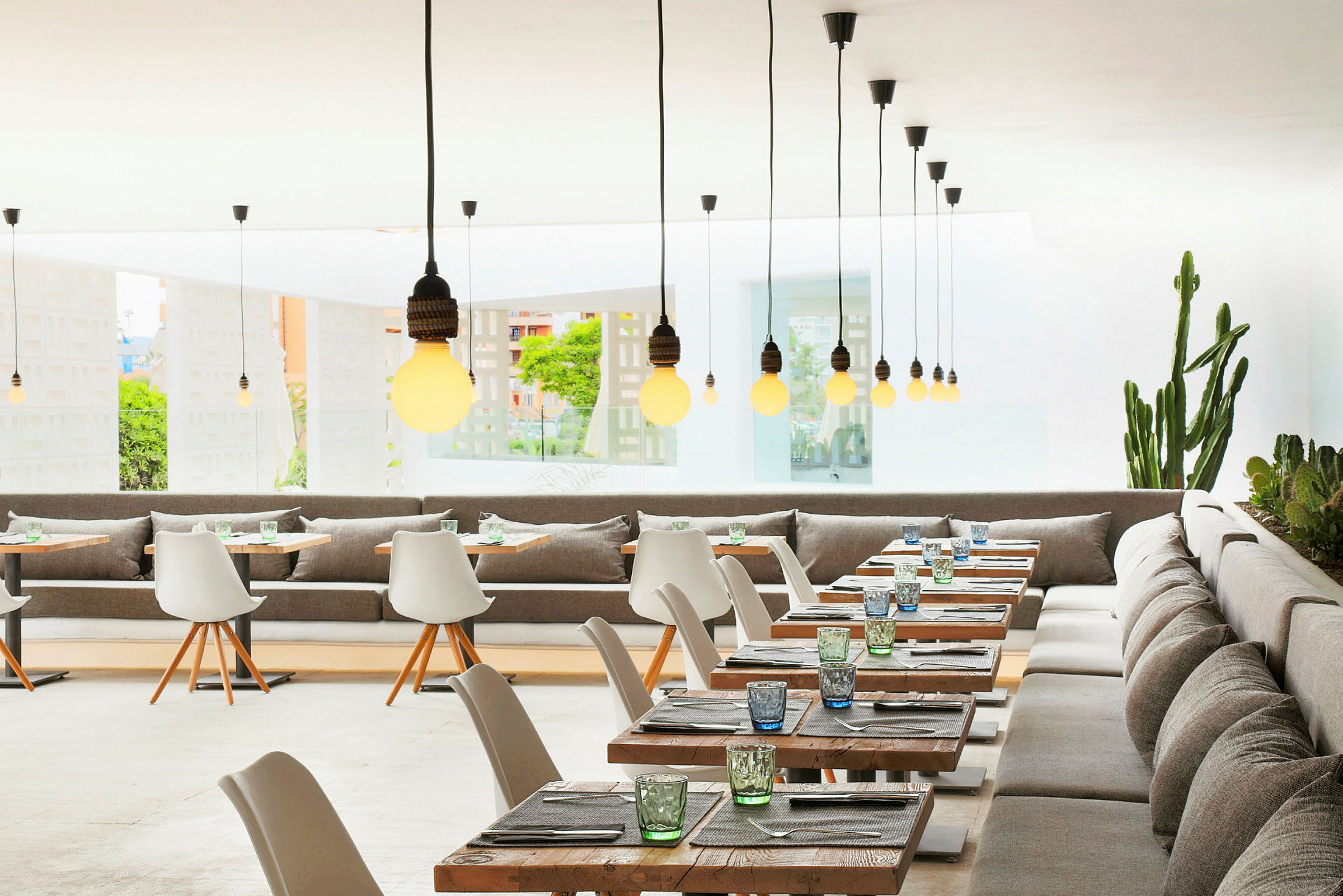 Restaurant med moderne indretning, borde og stole samt hængende lamper. (AI-genereret tekst)