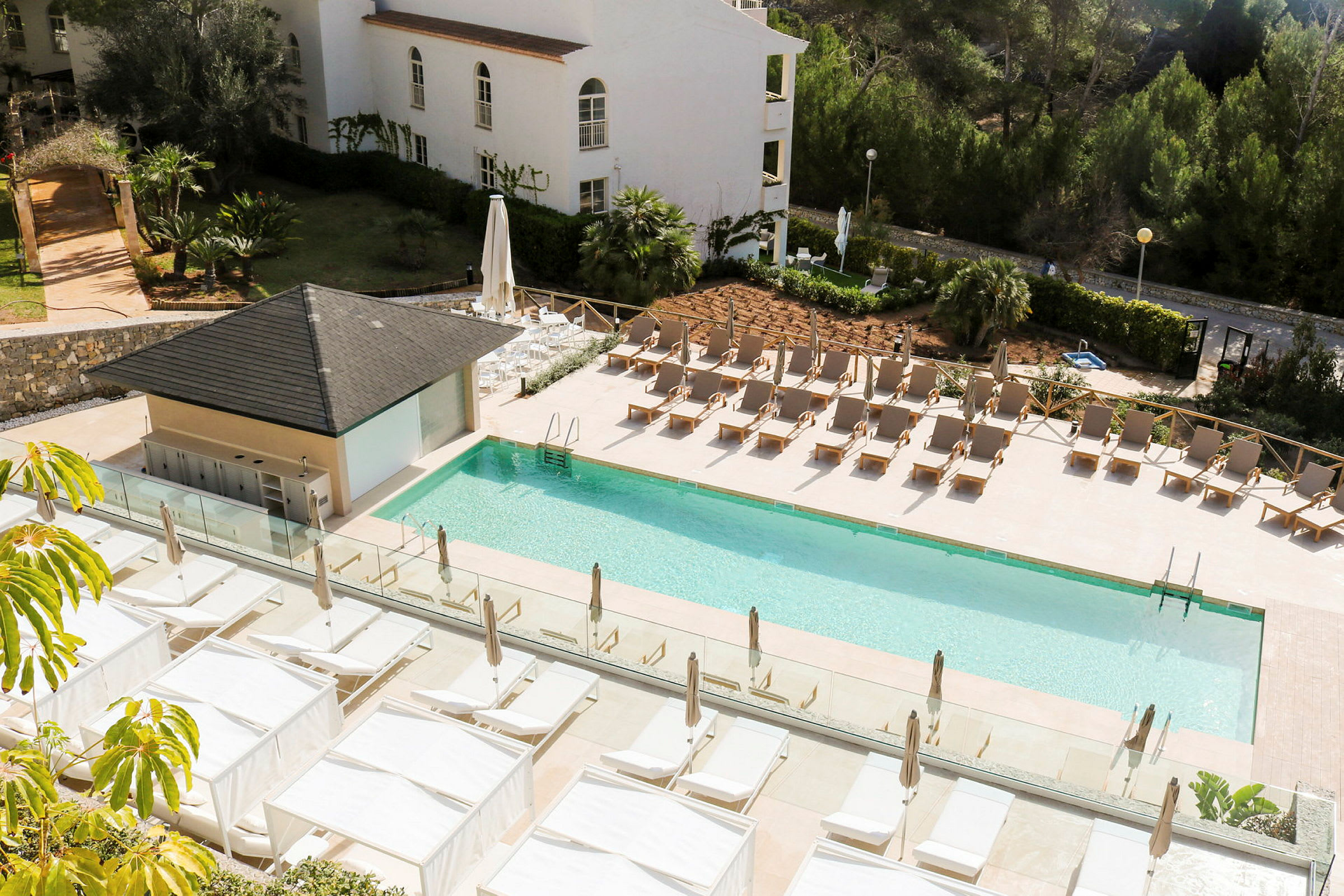 Udendørs pool med liggestole og baldakiner ved et hotel. (AI-genereret tekst)