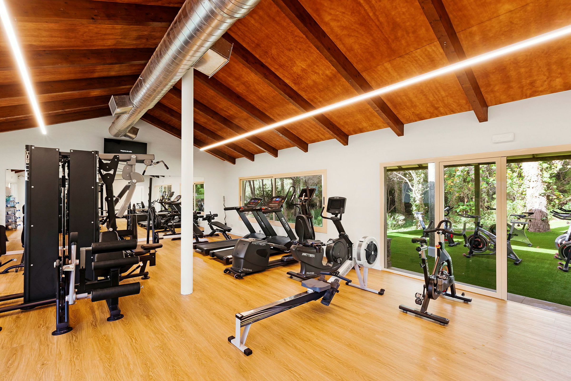 Fitnesscenter med træningsudstyr og store vinduer. (AI-genereret tekst)