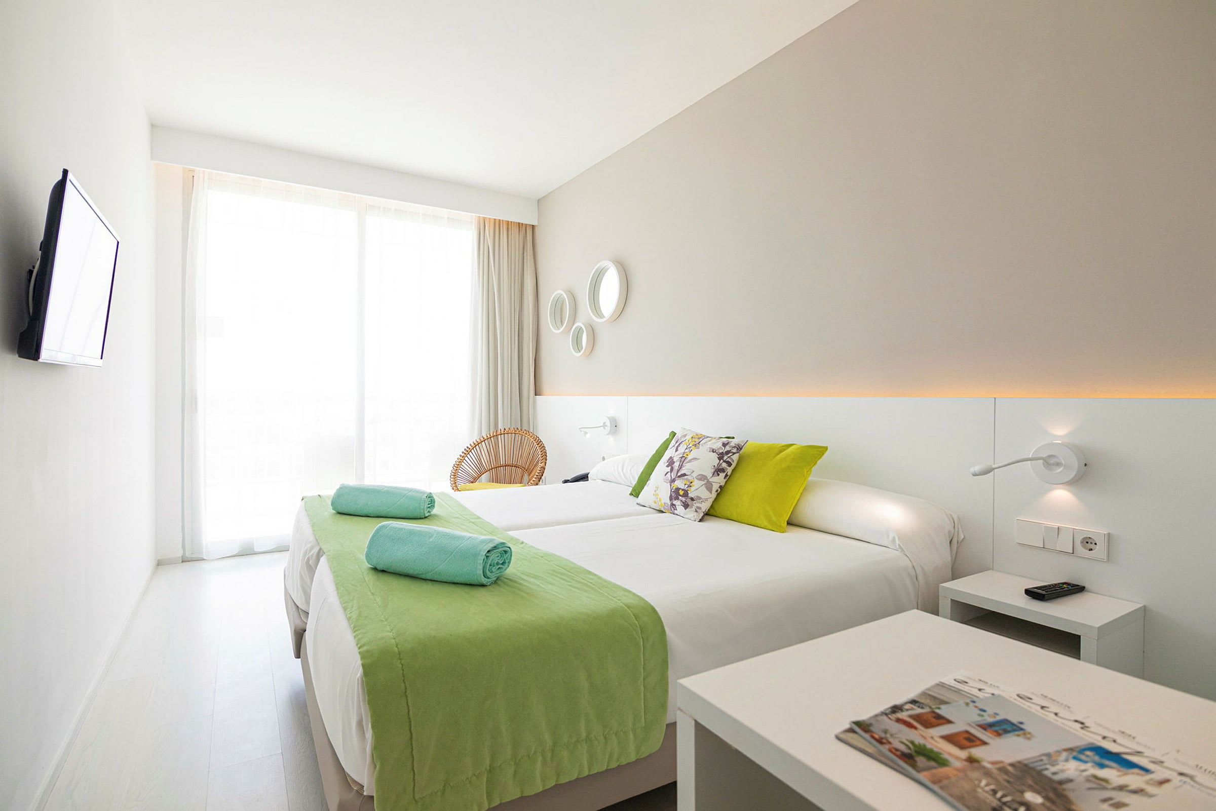 Et moderne hotelværelse med to enkeltsenge og grønne detaljer. (AI-genereret tekst)