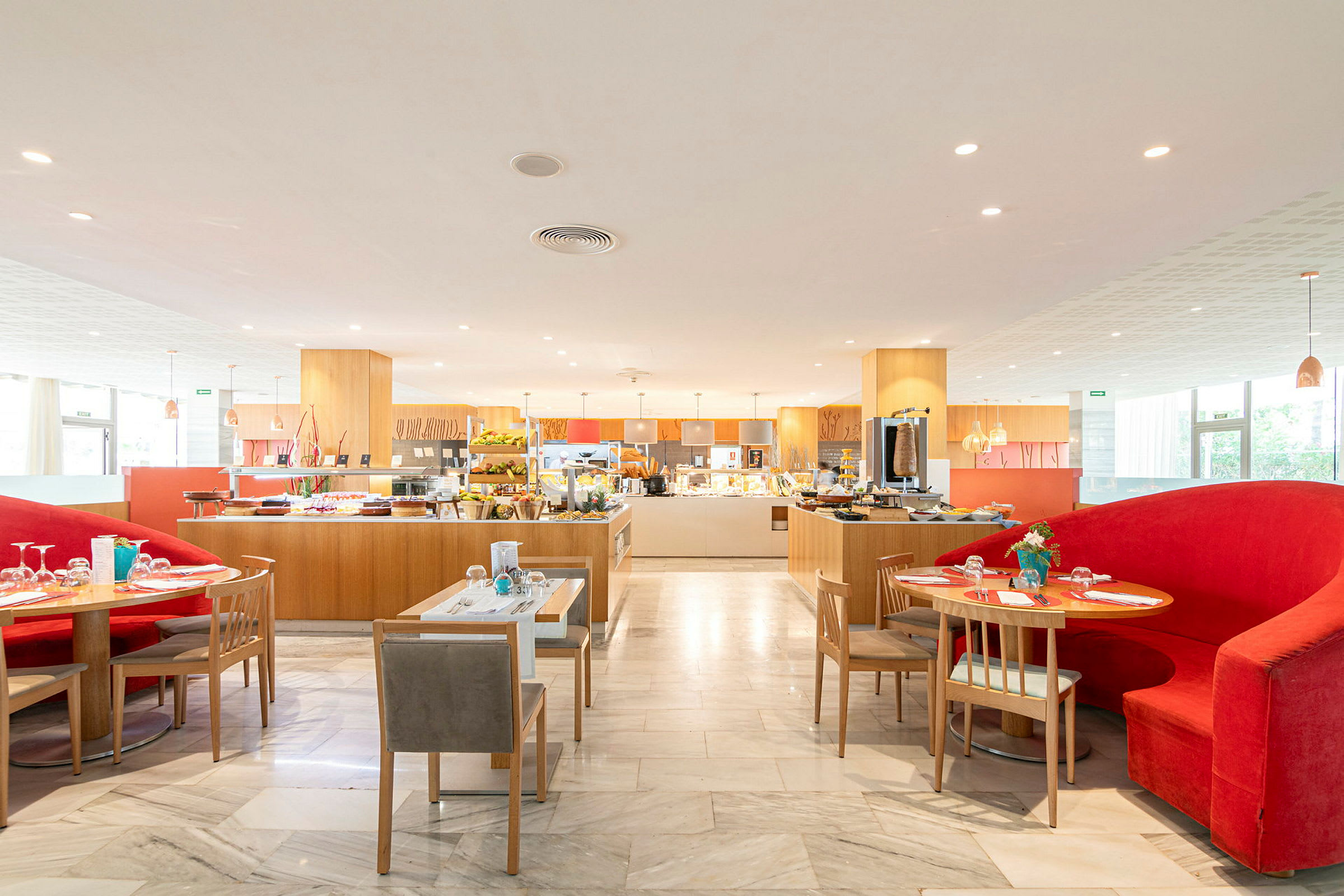 En restaurant med madbuffet og siddepladser. En rød sofa findes ved et bord i forgrunden. (AI-genereret tekst)
