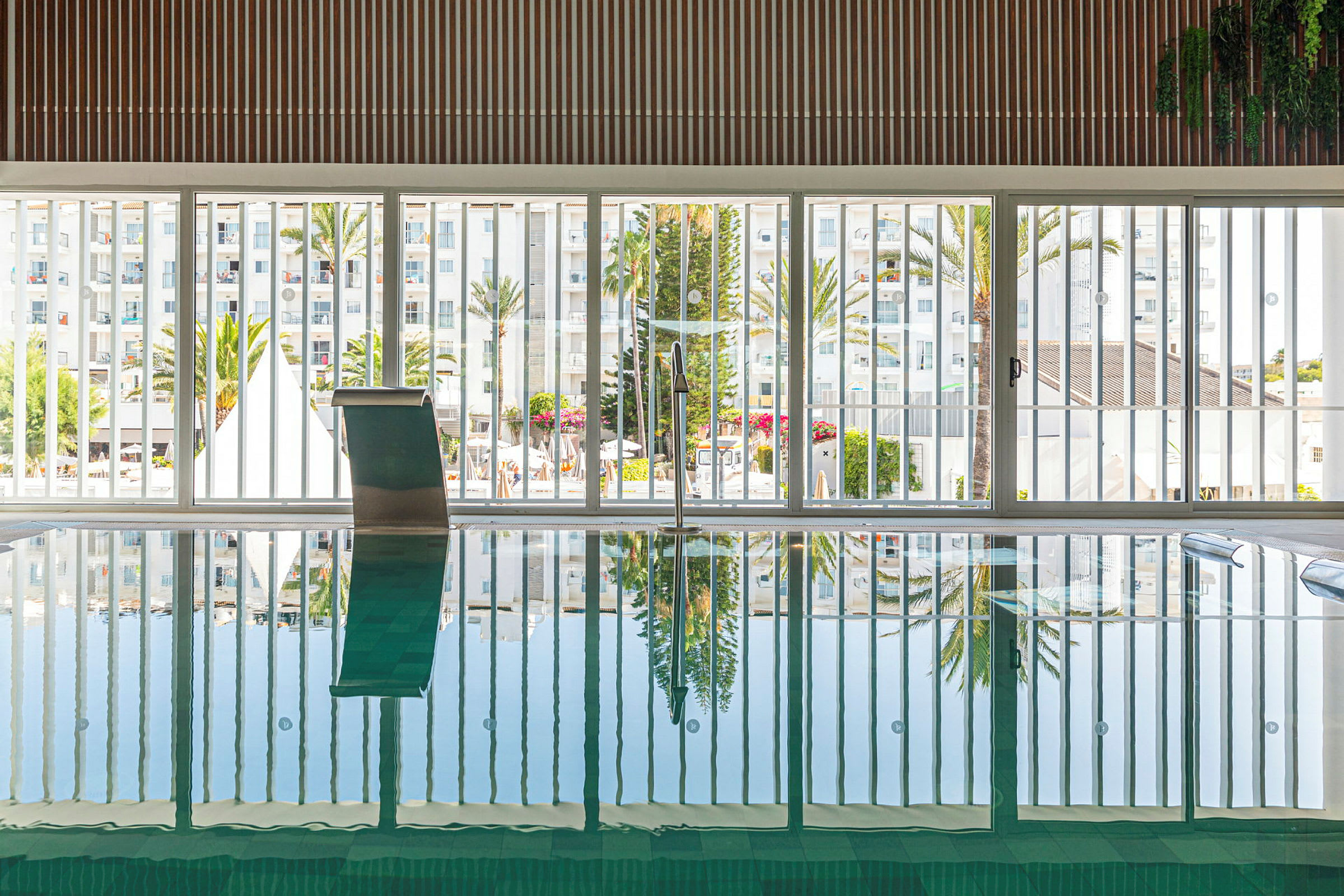 En indendørs pool med vinduer ud mod udendørsområdet. (AI-genereret tekst)