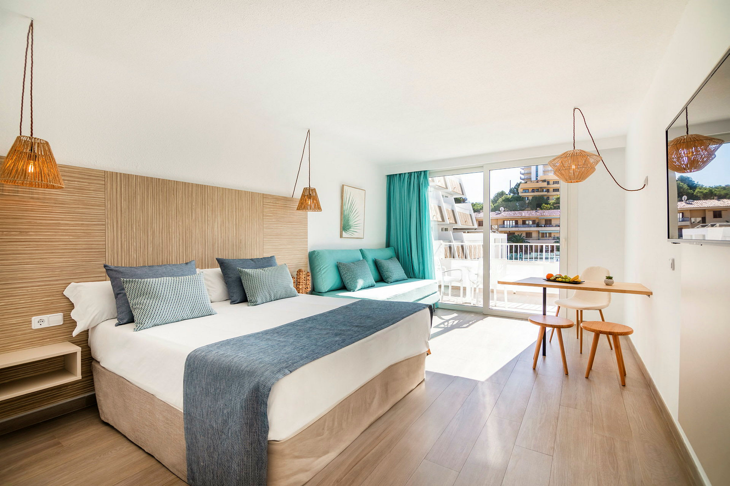 Hotelværelse med en dobbeltseng, en sofa med puder, et lille spiseområde og en altan. (AI-genereret tekst)