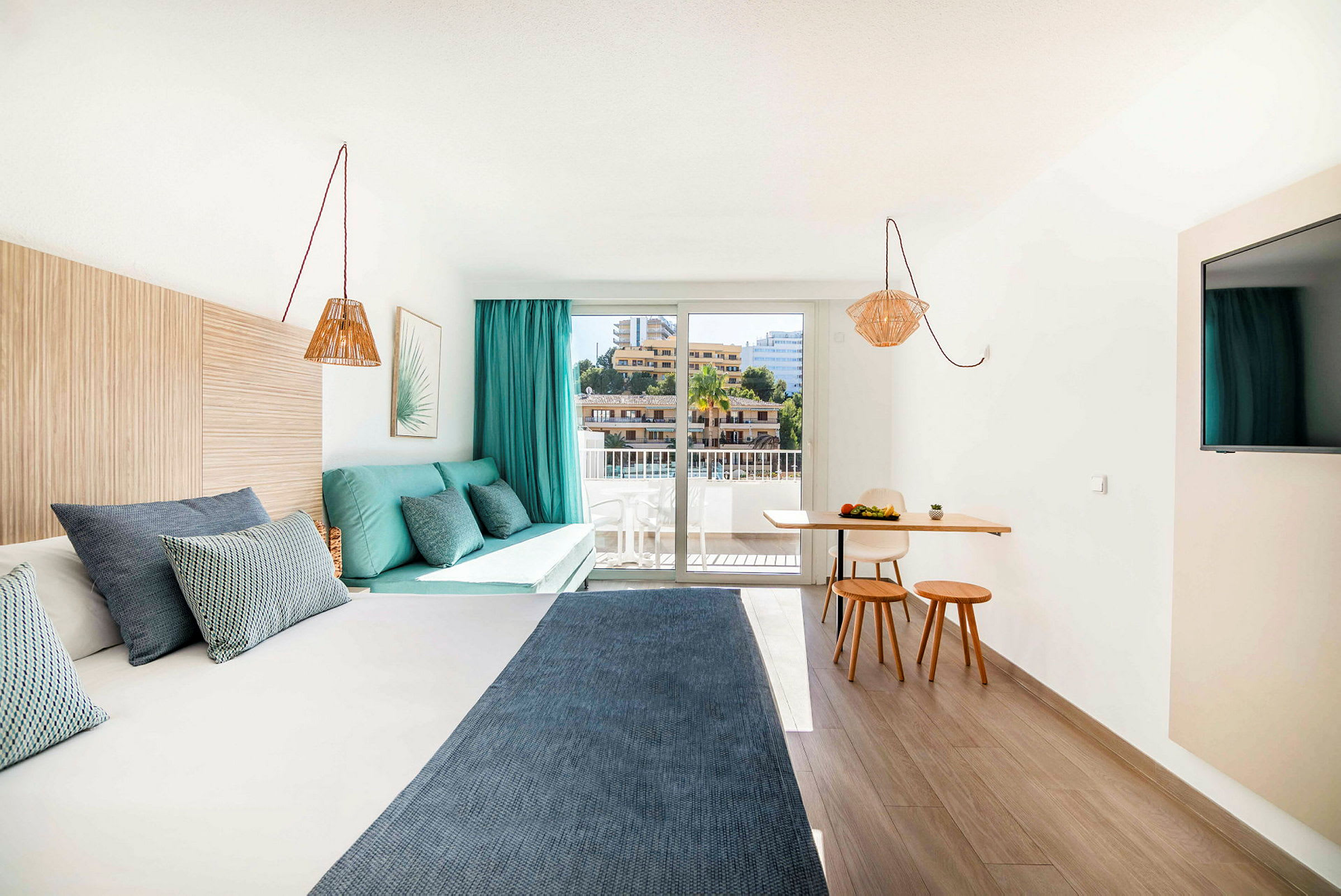 Et moderne hotelværelse med en seng, en siddegruppe og et lille spiseområde ved et stort vindue. (AI-genereret tekst)
