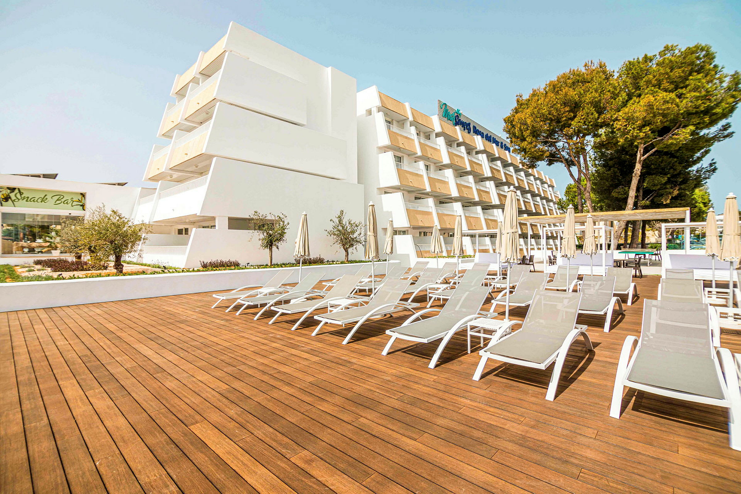 Billede af et hotel med liggestole på en træt terrasse. (AI-genereret tekst)
