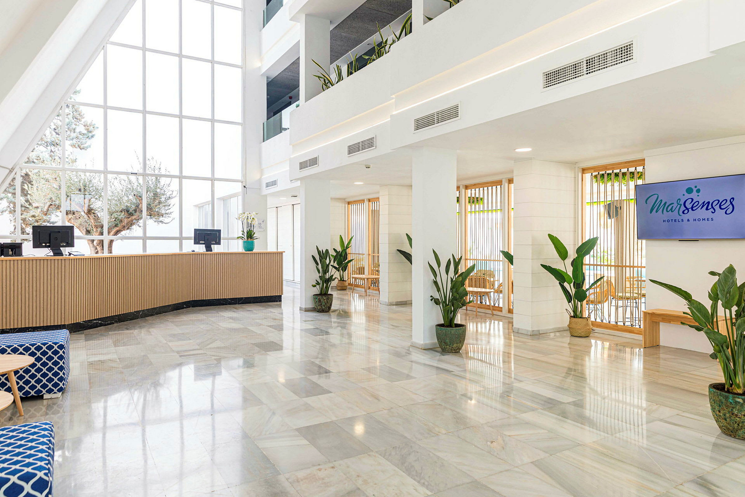 Hotelreception med store vinduer og planter. (AI-genereret tekst)