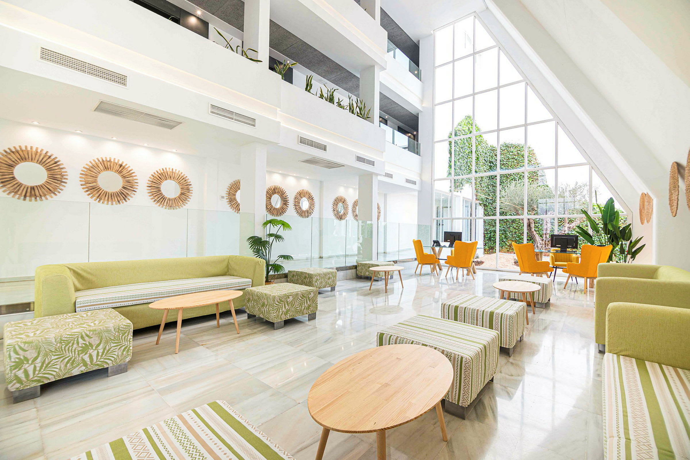 Moderne indrettet hotellobby med store vinduer og grønne elementer. (AI-genereret tekst)