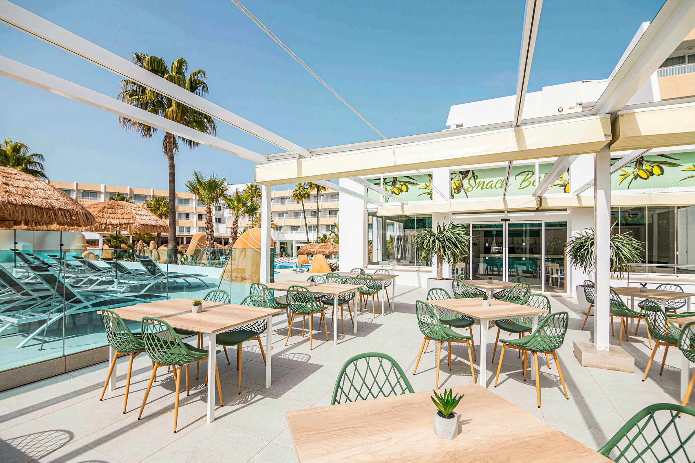 En terrasse med spiseborde og stole, omgivet af en pool og palmetræer. (AI-genereret tekst)