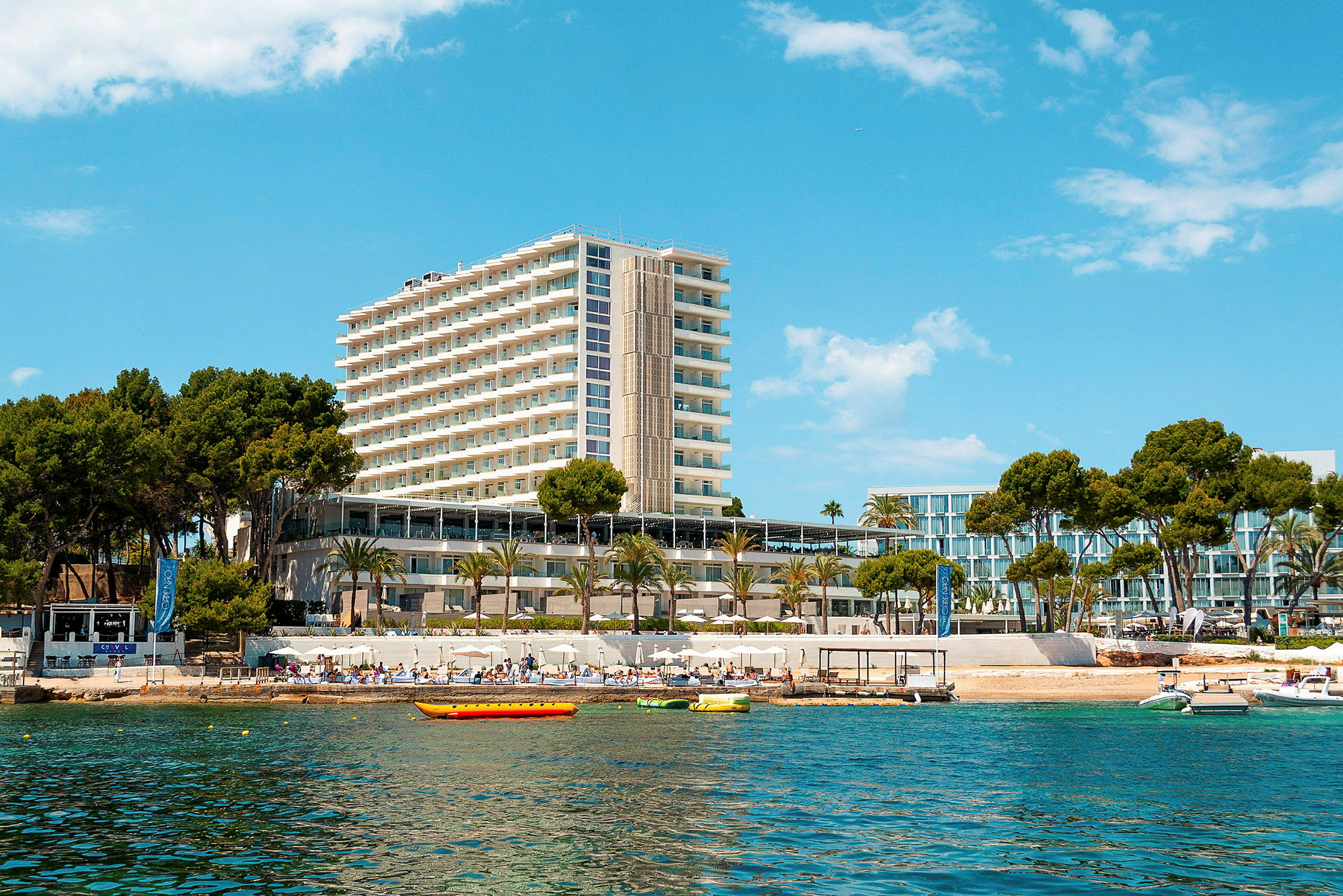 Højt hotel ved stranden med blå himmel. (AI-genereret tekst)