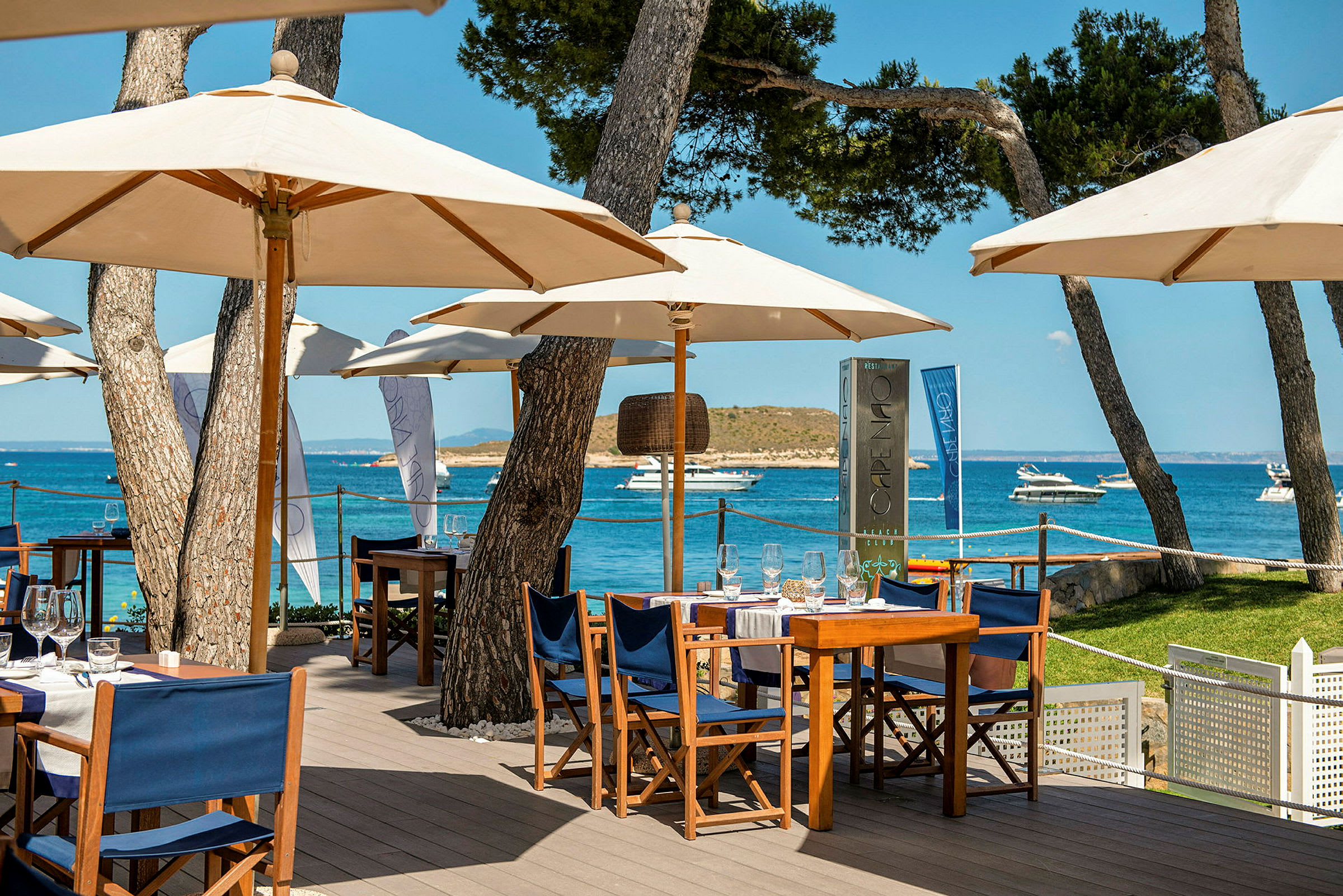 Udendørsrestaurant med parasoller og borde ved havet. (AI-genereret tekst)