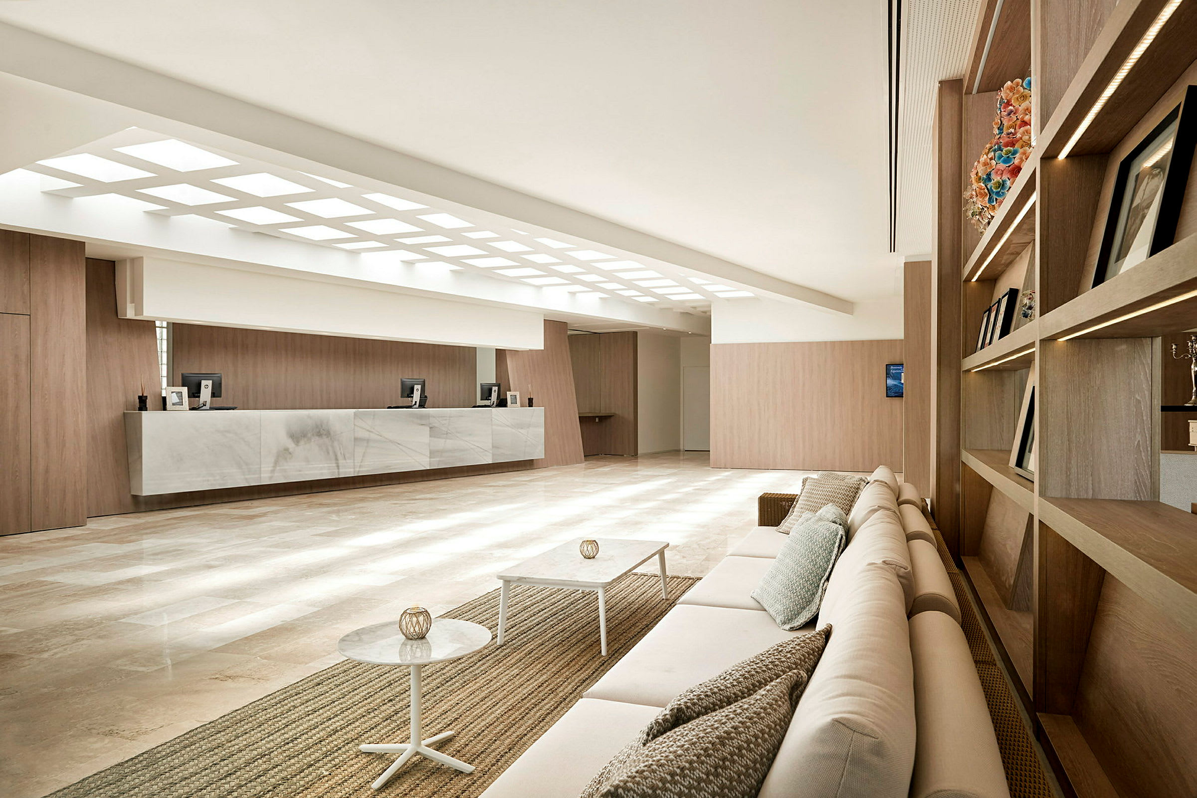 Billede af en moderne hotellobby med en siddegruppe, receptionsområde og minimalistisk indretning. (AI-genereret tekst)