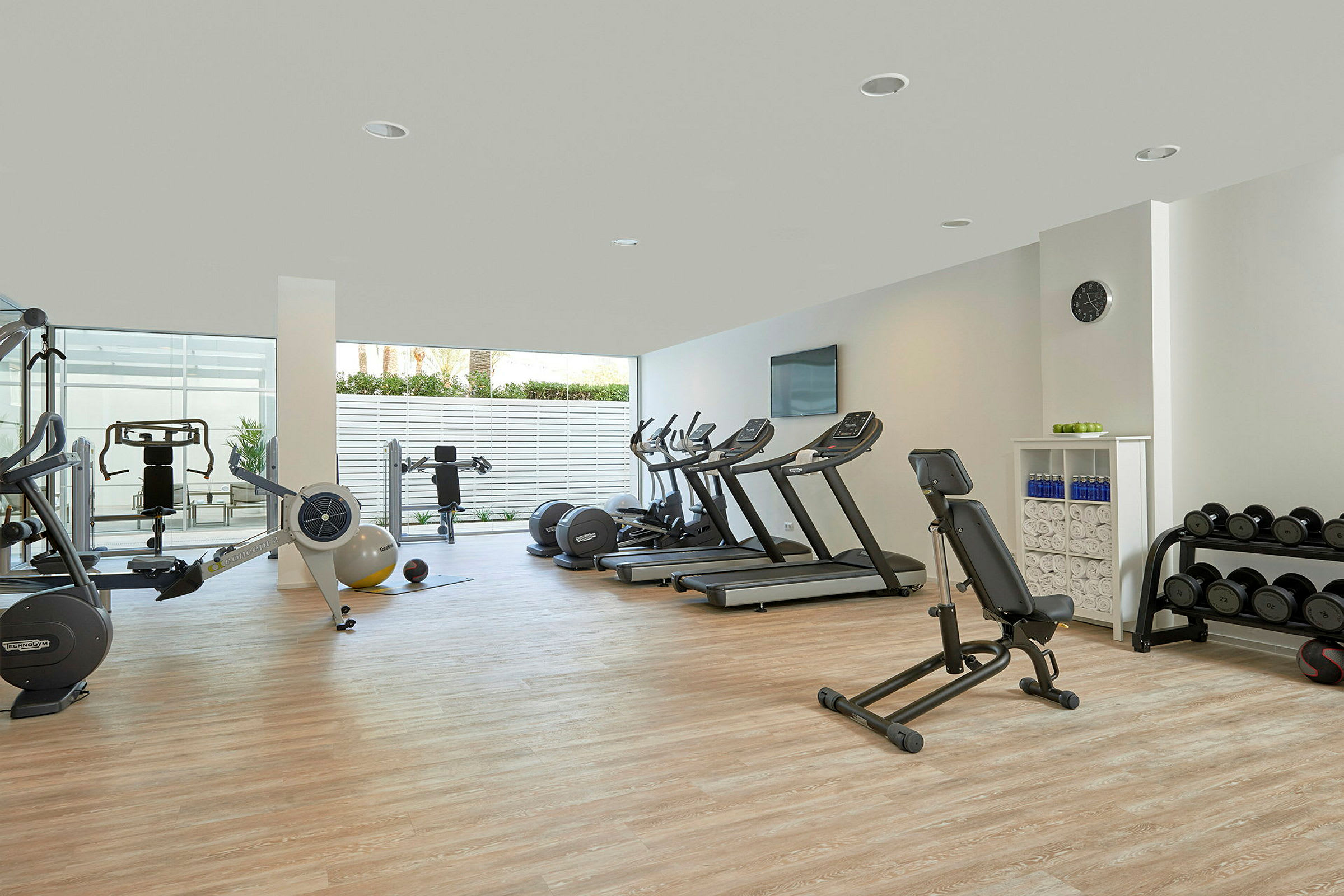 Et fitnesscenter med træningsmaskiner, løbebånd og vægte i et åbent og lyst rum. (AI-genereret tekst)