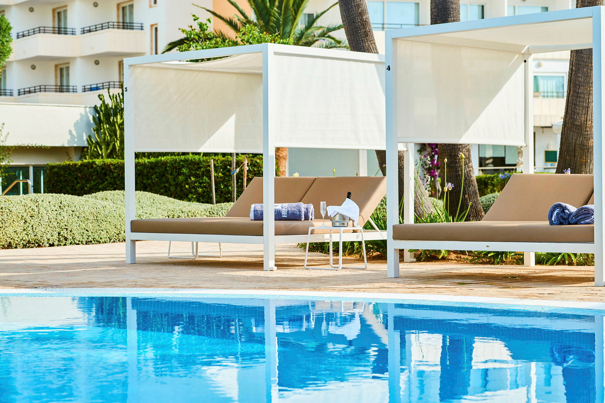 To liggestole med parasoller ved siden af en swimmingpool. (AI-genereret tekst)