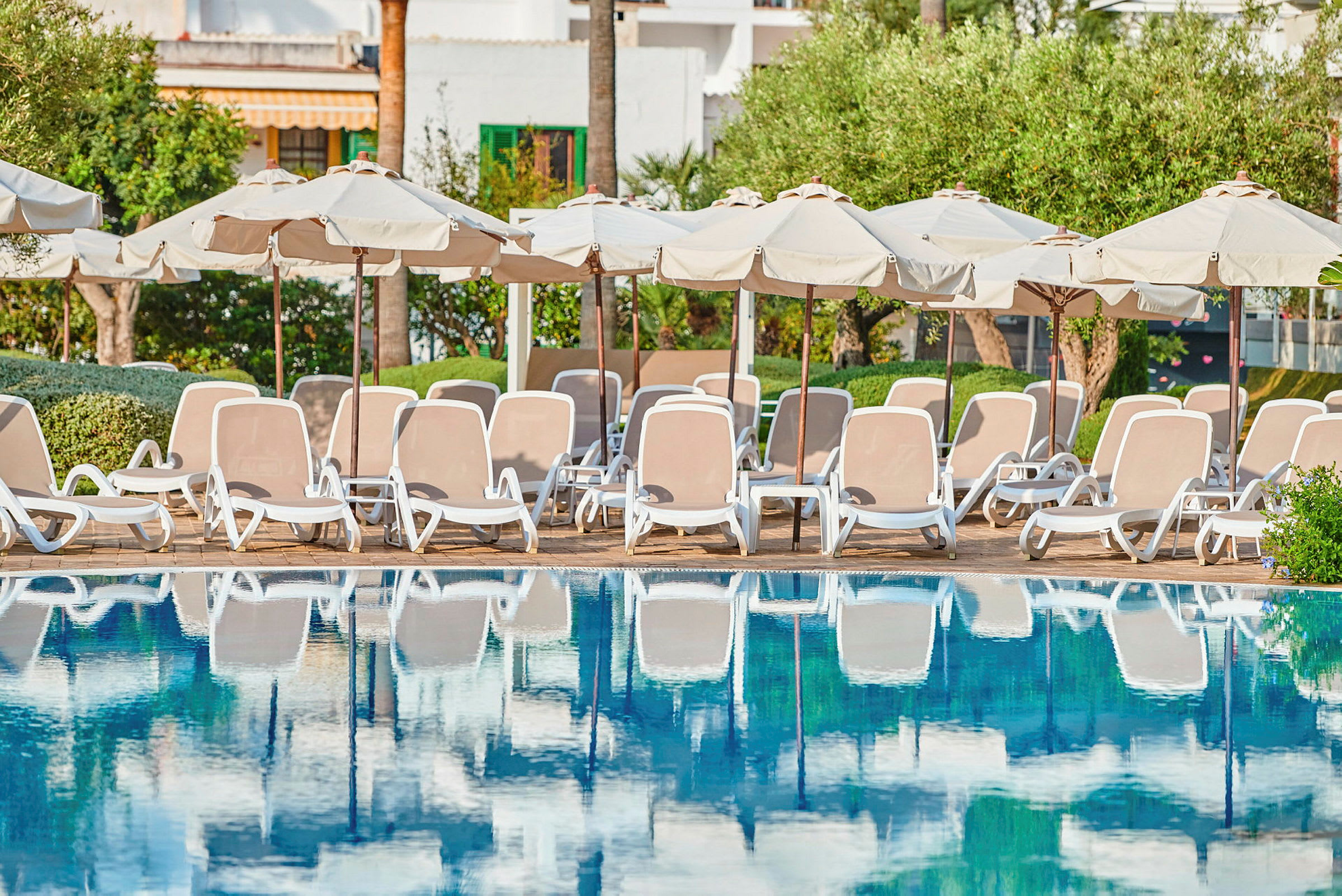 Liggestole og parasoller ved kanten af en pool. (AI-genereret tekst)