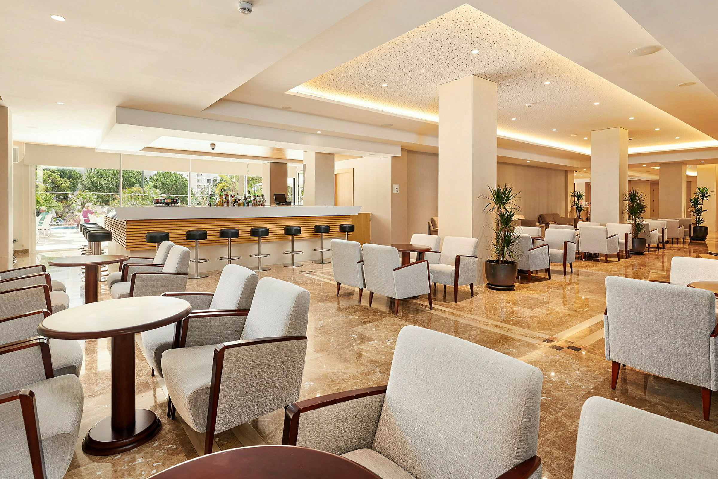 Elegant hotel lounge med komfortable grå stole og sofaborde, samt bar med høje stole. (AI-genereret tekst)
