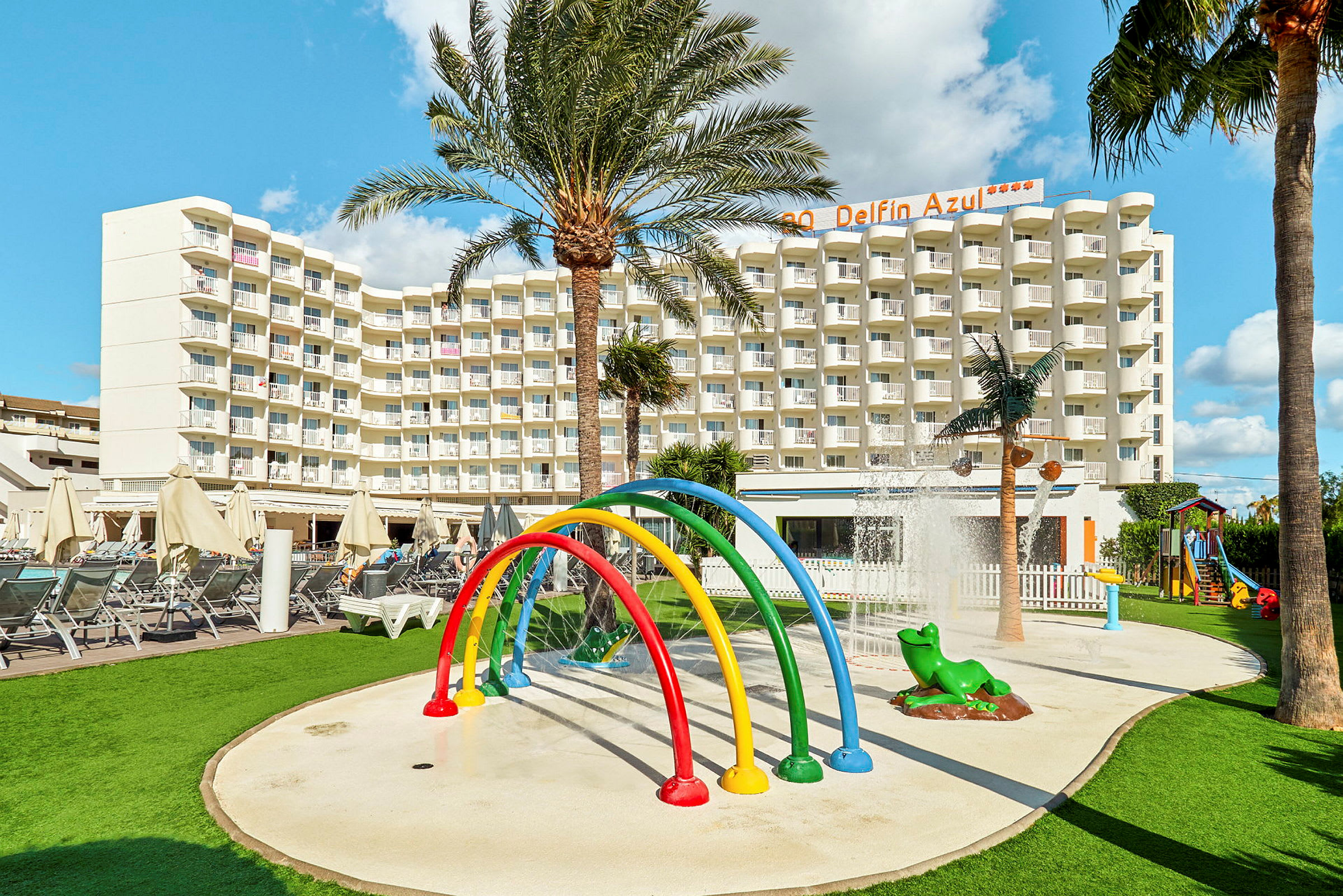 Billede af et hotel med en legeplads og springvand i forgrunden. (AI-genereret tekst)