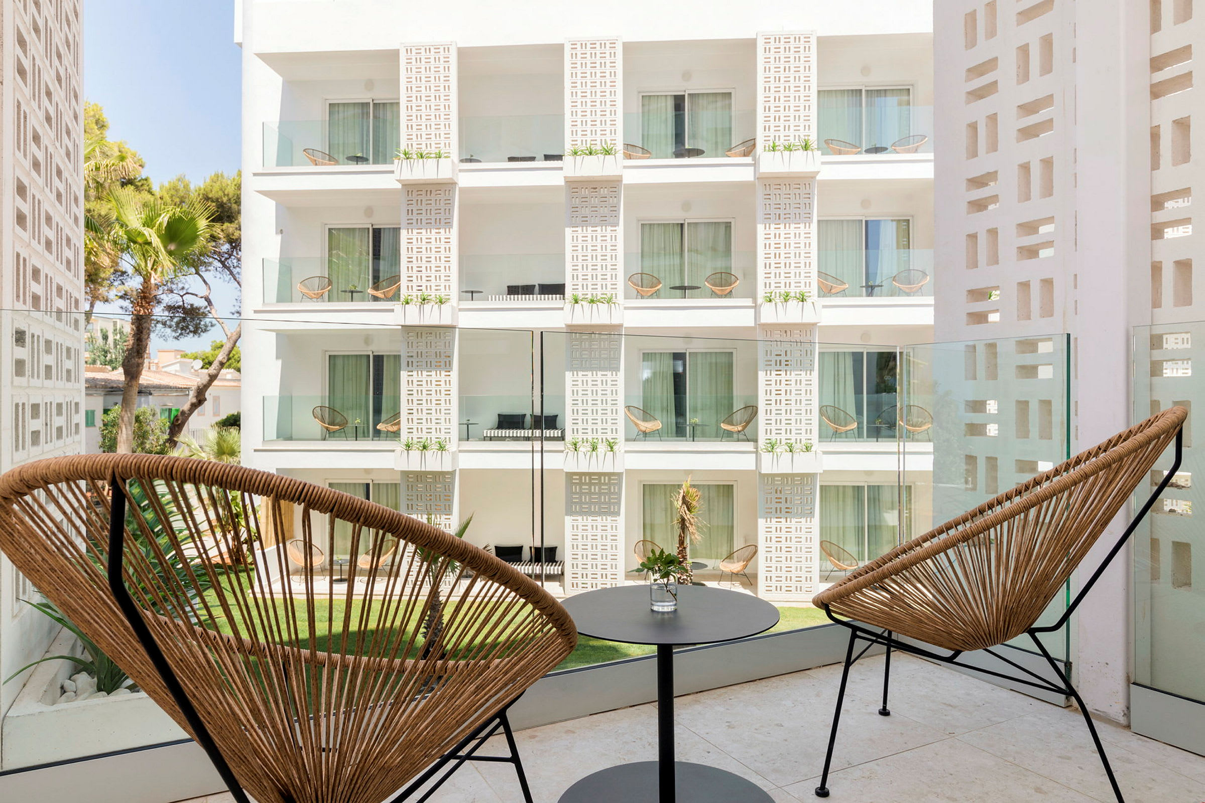 Hotelbalkon med to stole og et lille bord med udsigt til en bygnings facade. (AI-genereret tekst)