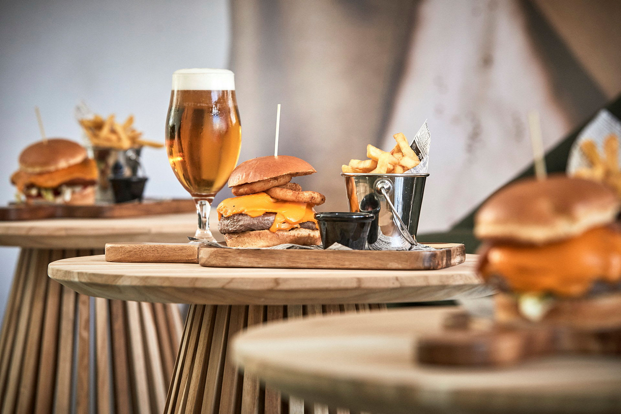 Tallerkener med burgere, pommes frites i metalspand og glas med øl på træbord. (AI-genereret tekst)