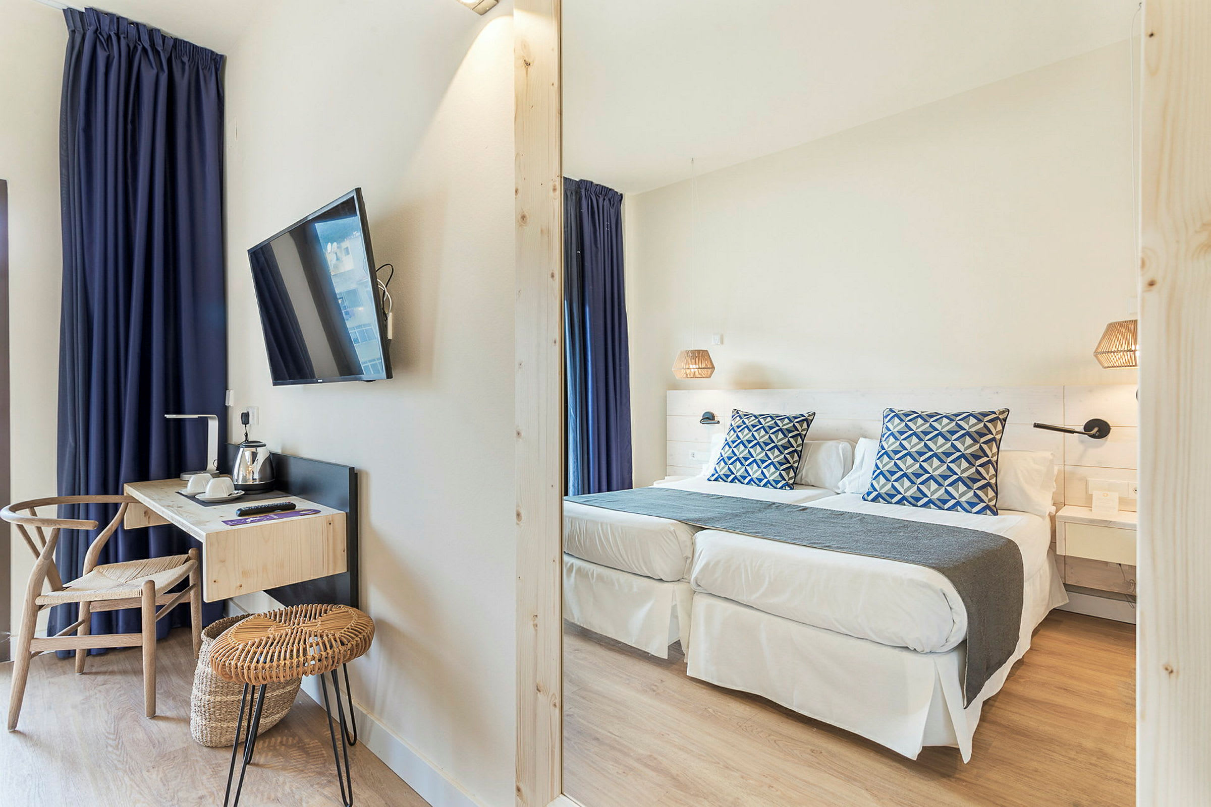Hotelværelse med to enkeltsenge, skrivebord og TV. (AI-genereret tekst)