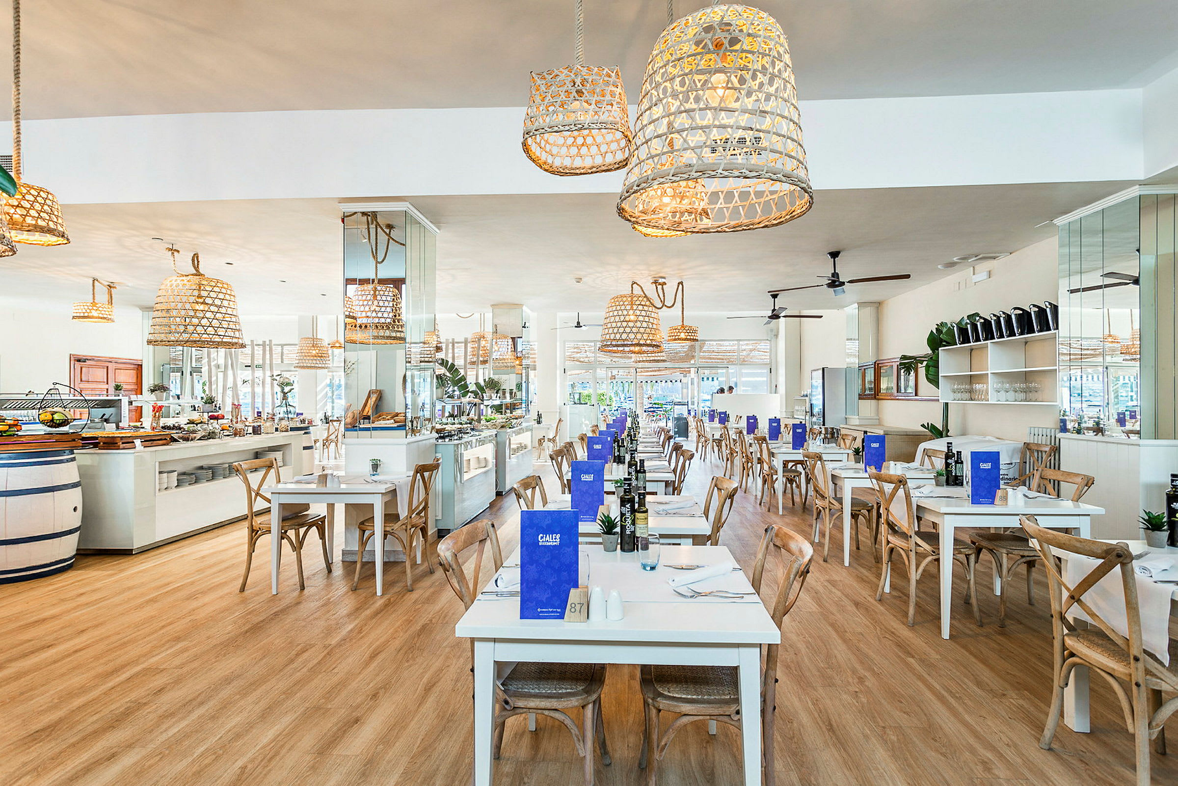 Restaurant med hvide borde og træstole, dekoreret med hængende flettede lamper. (AI-genereret tekst)