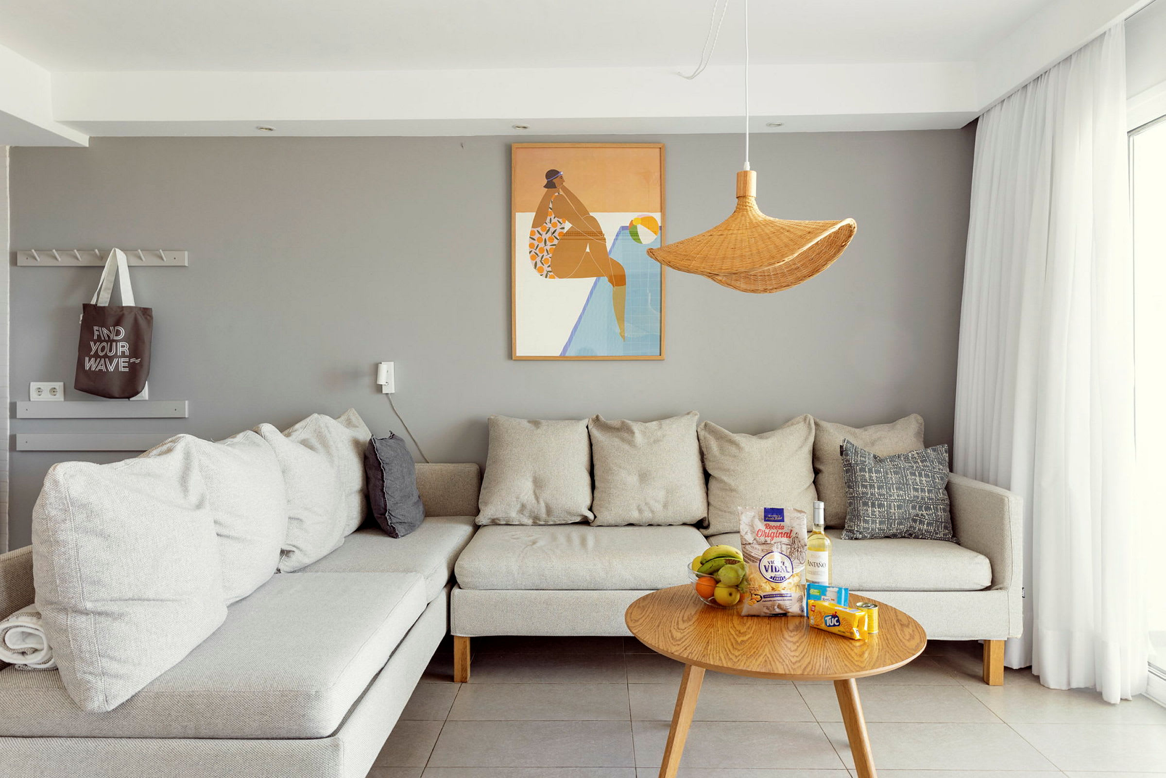 Billede af en moderne stue med en grå væg, grå sofa og et træbord med snacks og drikkevarer. (AI-genereret tekst)