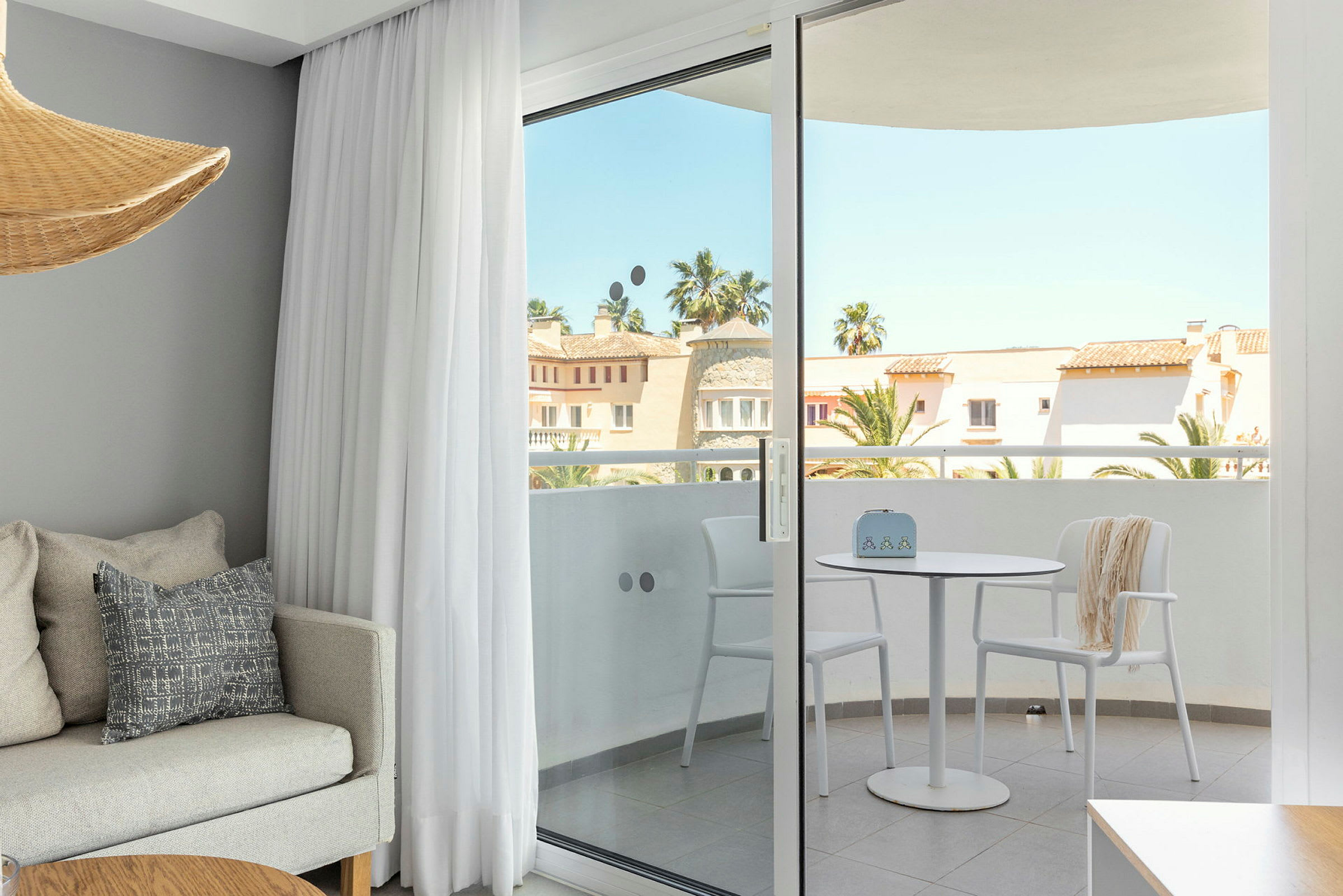 Interiør af et værelse med en sofa og et bord samt udsigt til en balkon med bord og stole. (AI-genereret tekst)