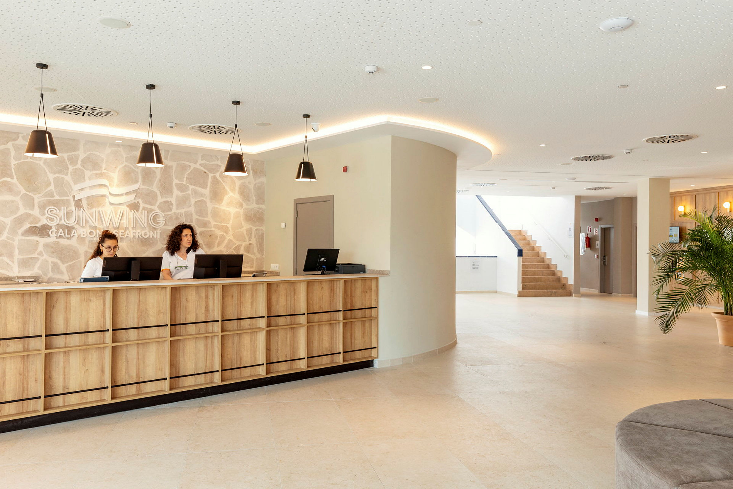 Receptionen på Sunwing Cala Bona Seafront med træpaneler og en stenmur. (AI-genereret tekst)