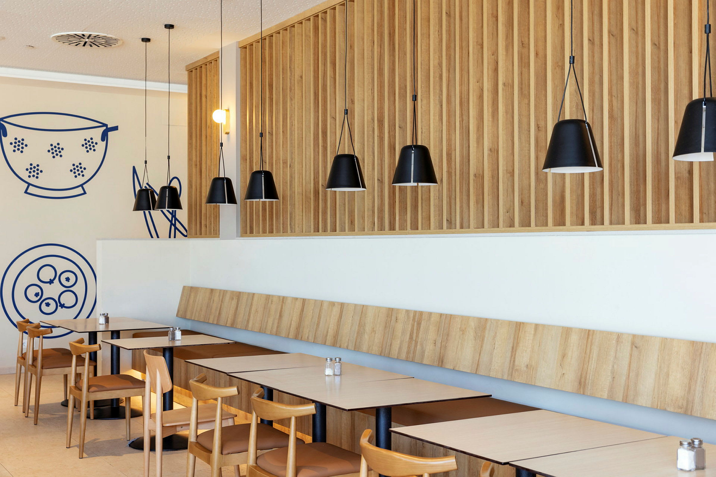 En moderne restaurant med træpaneler og sorte hængelamper. (AI-genereret tekst)