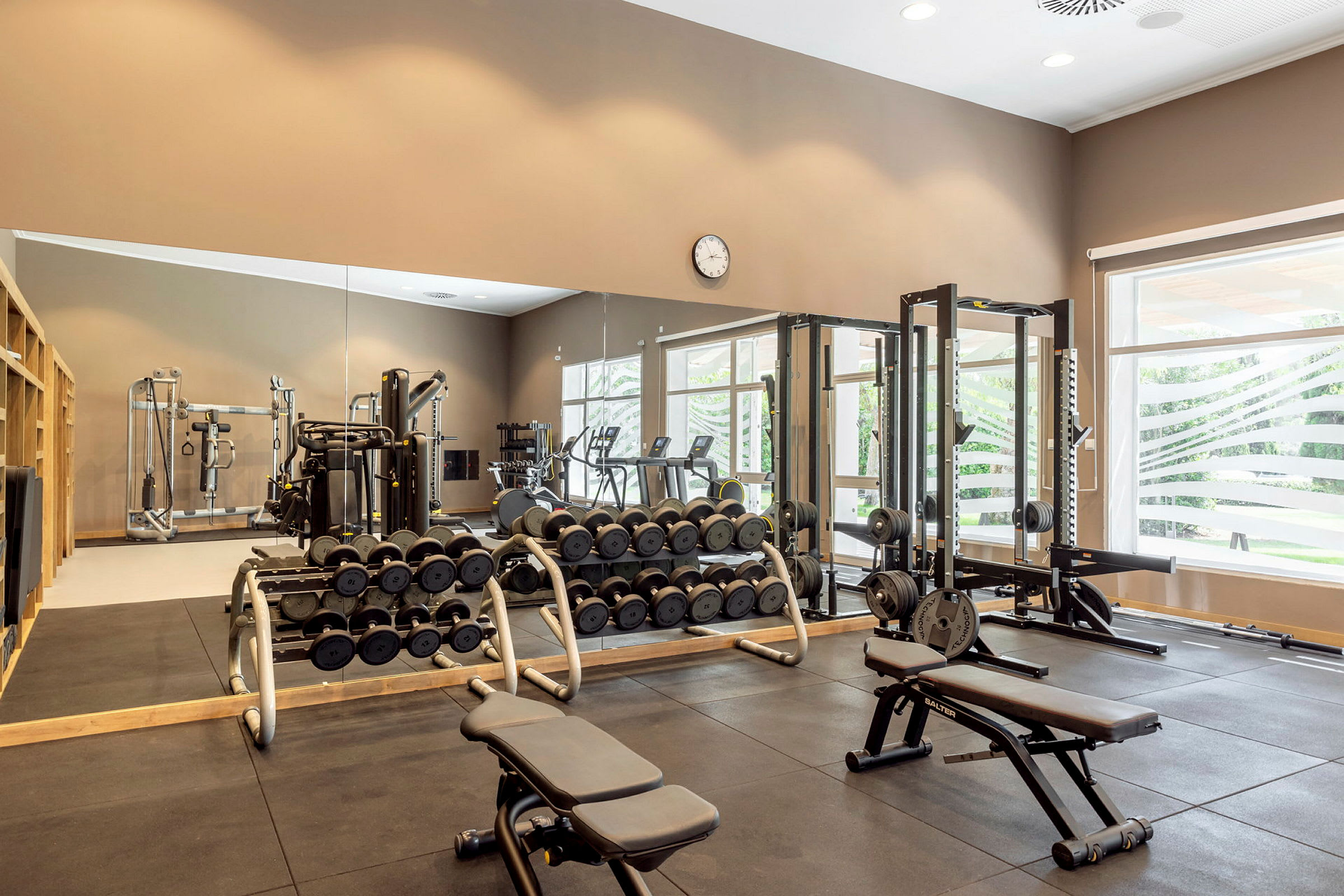 Billede af et fitnesscenter med forskellige træningsmaskiner og frie vægte. (AI-genereret tekst)