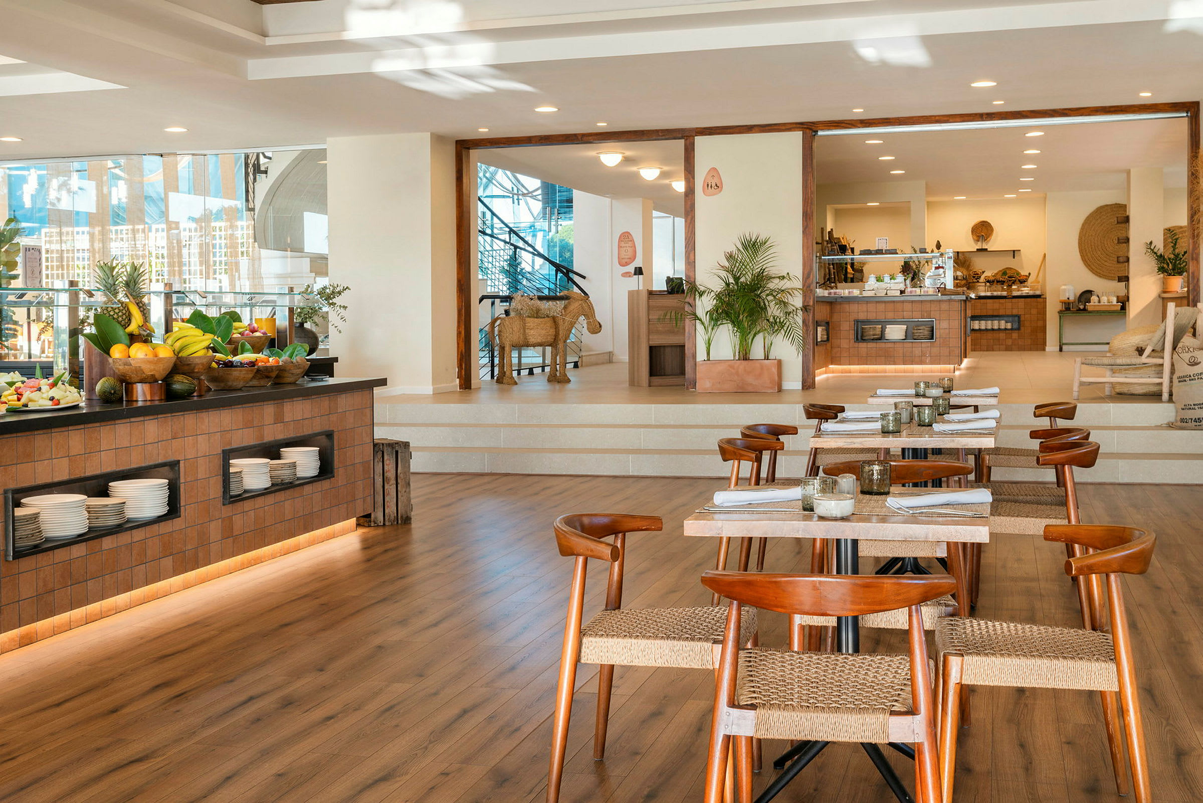 En restaurant med træborde og stole samt en buffet med frugt og serveringsfade. (AI-genereret tekst)