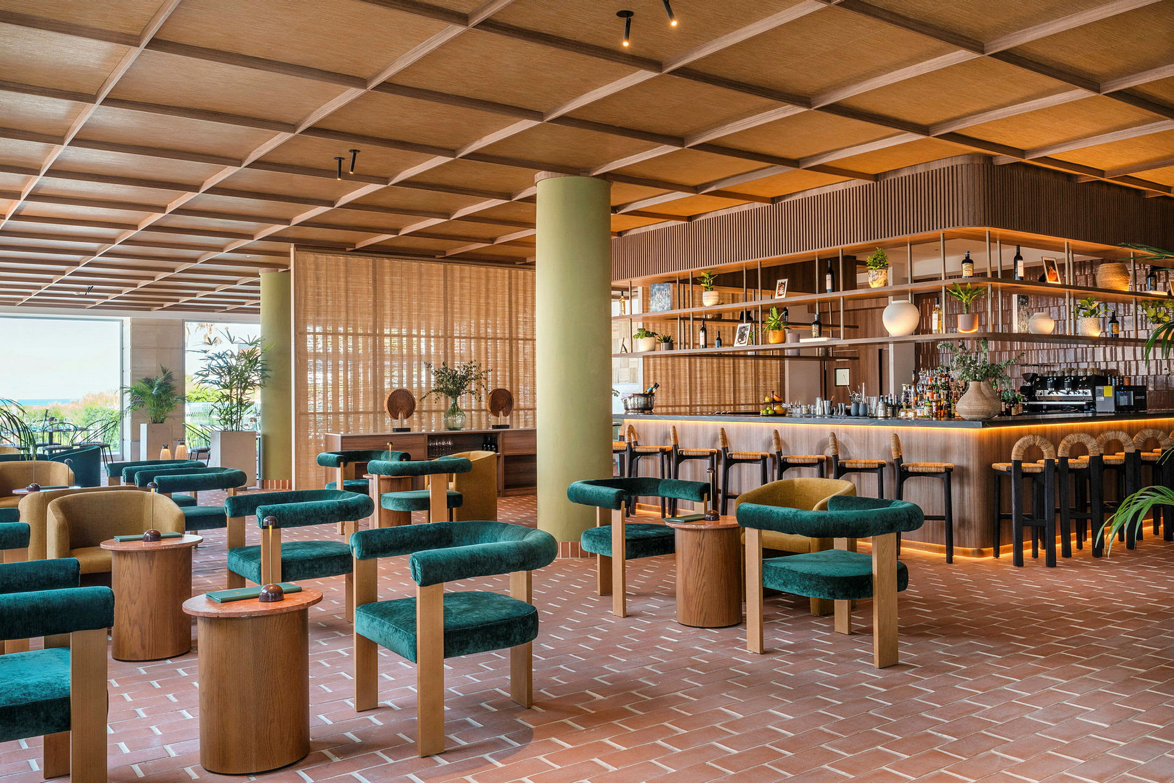 Billede af en moderne bar eller restaurant med grønne siddepladser, træborde og en velorganiseret bardisk. Interiøret har en varm og indbydende atmosfære. (AI-genereret tekst)