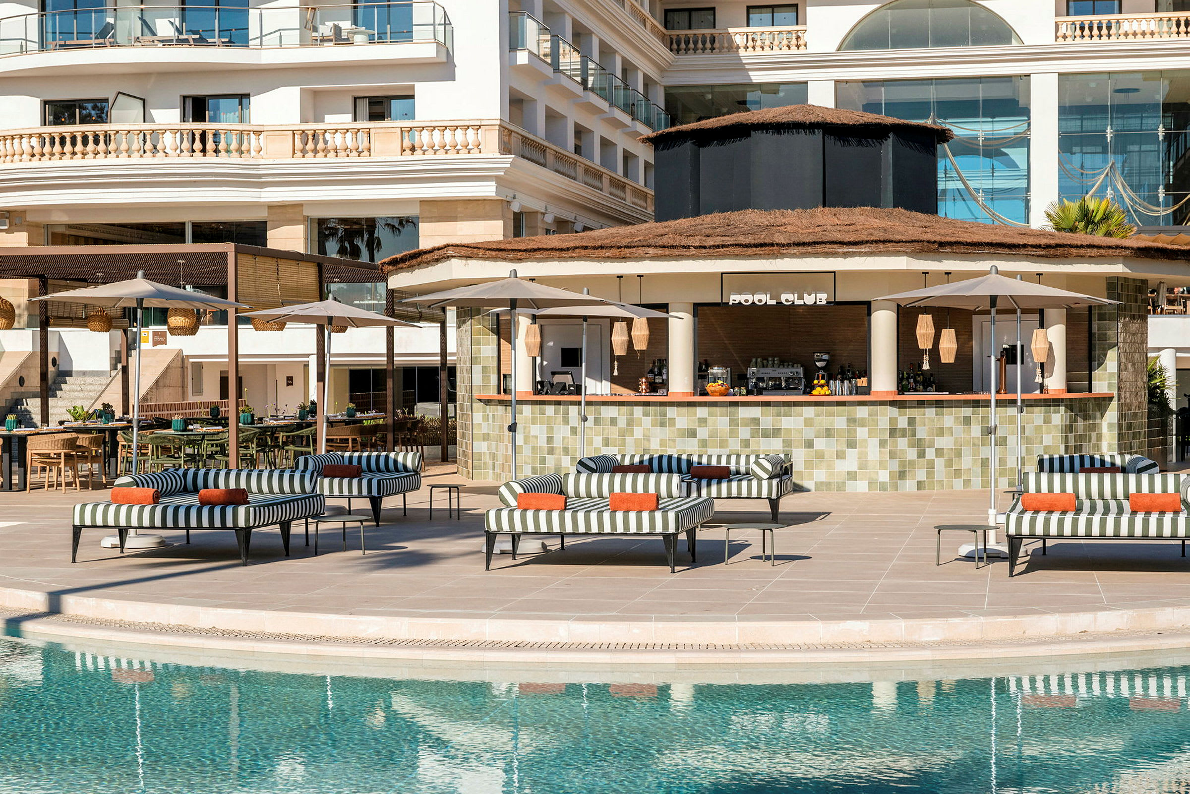 En pool med liggestole, parasoller og en bar med skiltet "Pool Club" i baggrunden. (AI-genereret tekst)
