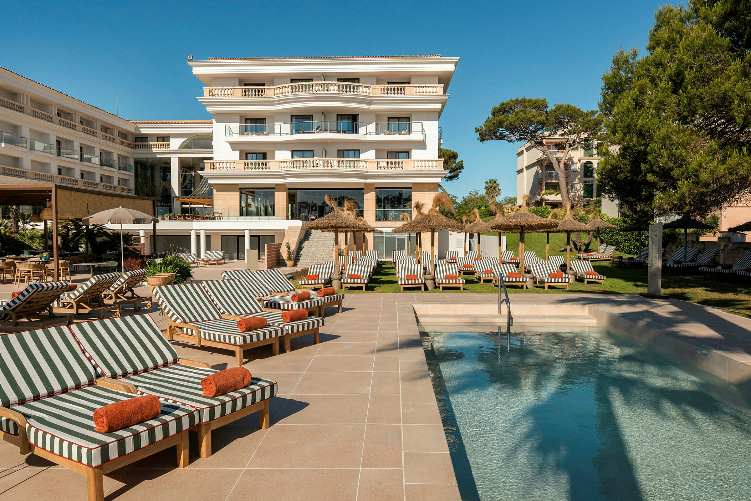 Et billede af et hotel med en udendørs pool, liggestole og parasoller. (AI-genereret tekst)