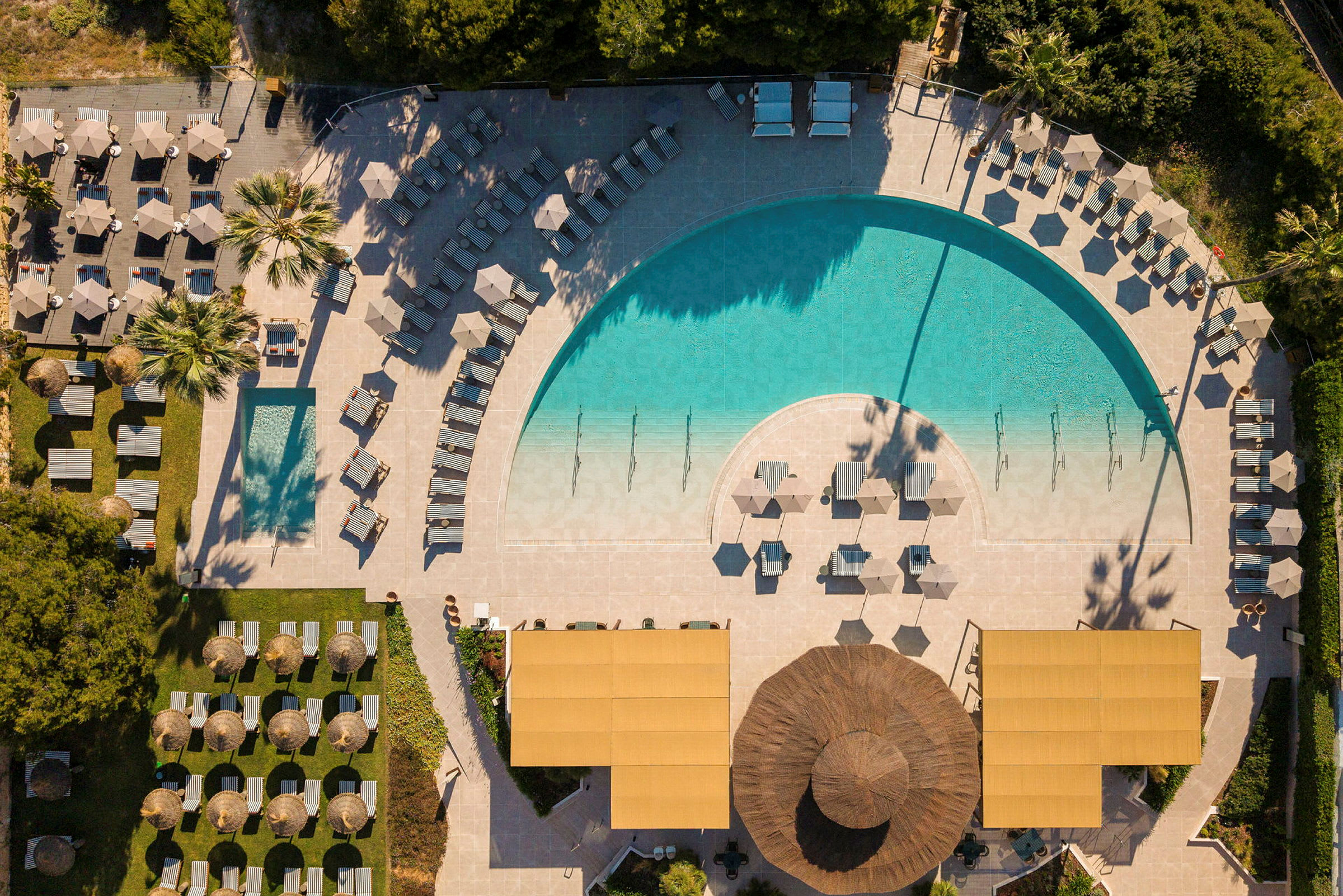 Luftfoto af en pool omgivet af liggestole og parasoller på terrassen. (AI-genereret tekst)