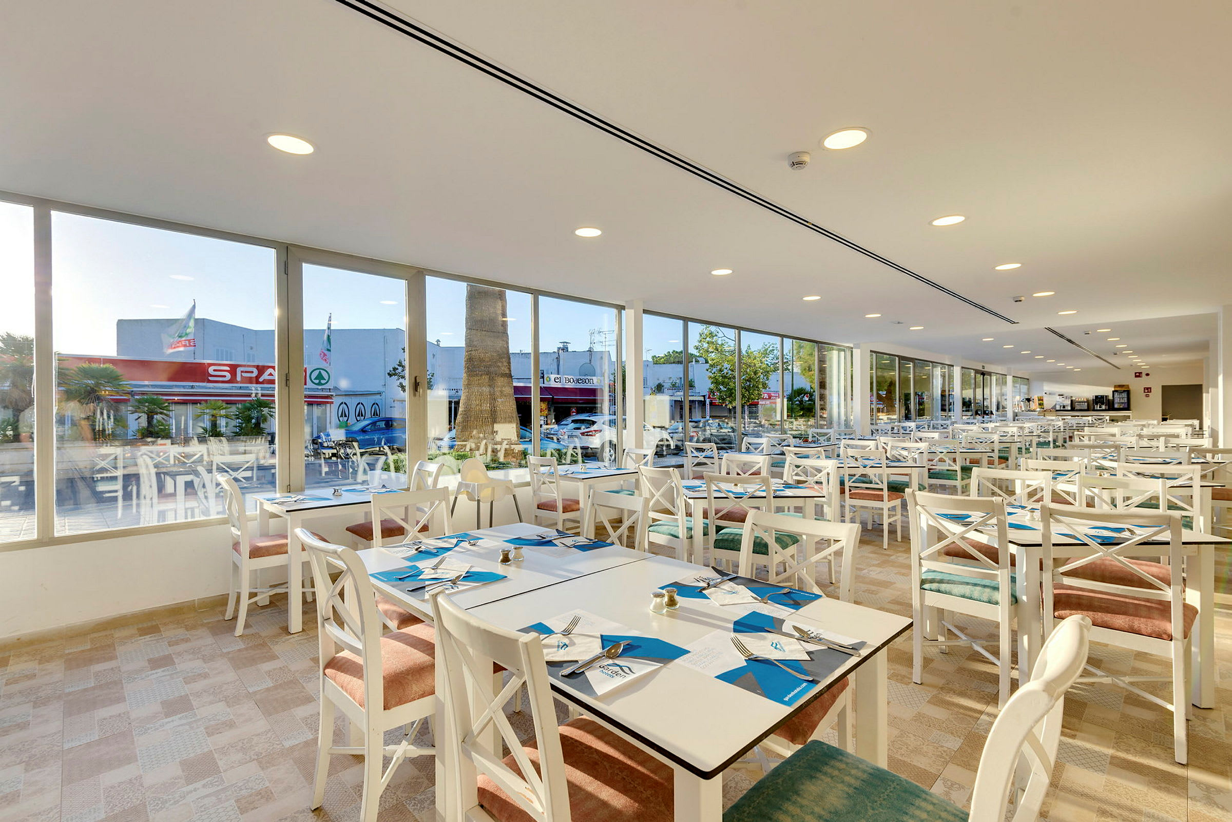 Restaurant med hvide møbler og vinduer mod gaden. (AI-genereret tekst)