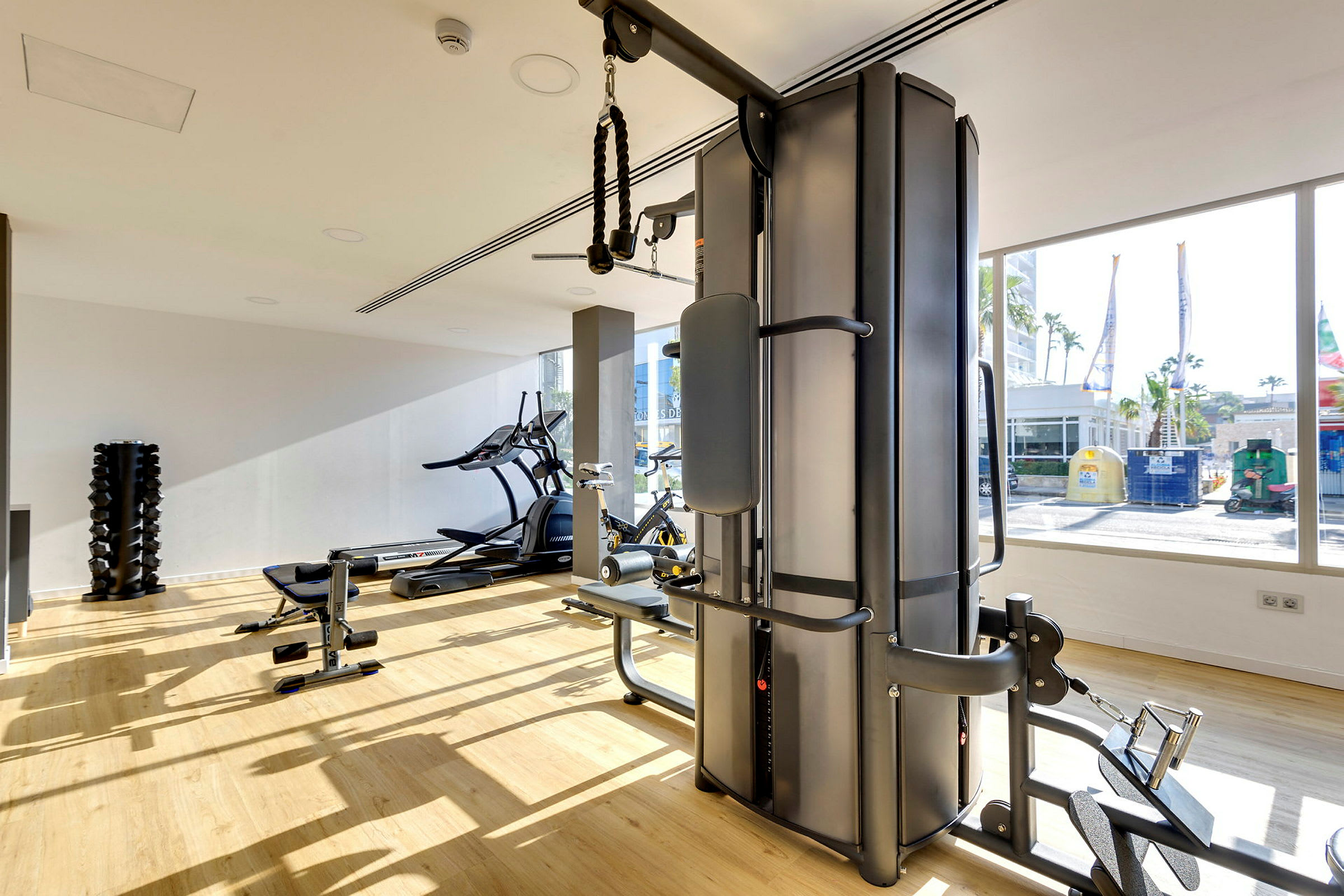 Fitnesscenter med træningsudstyr og store vinduer. (AI-genereret tekst)