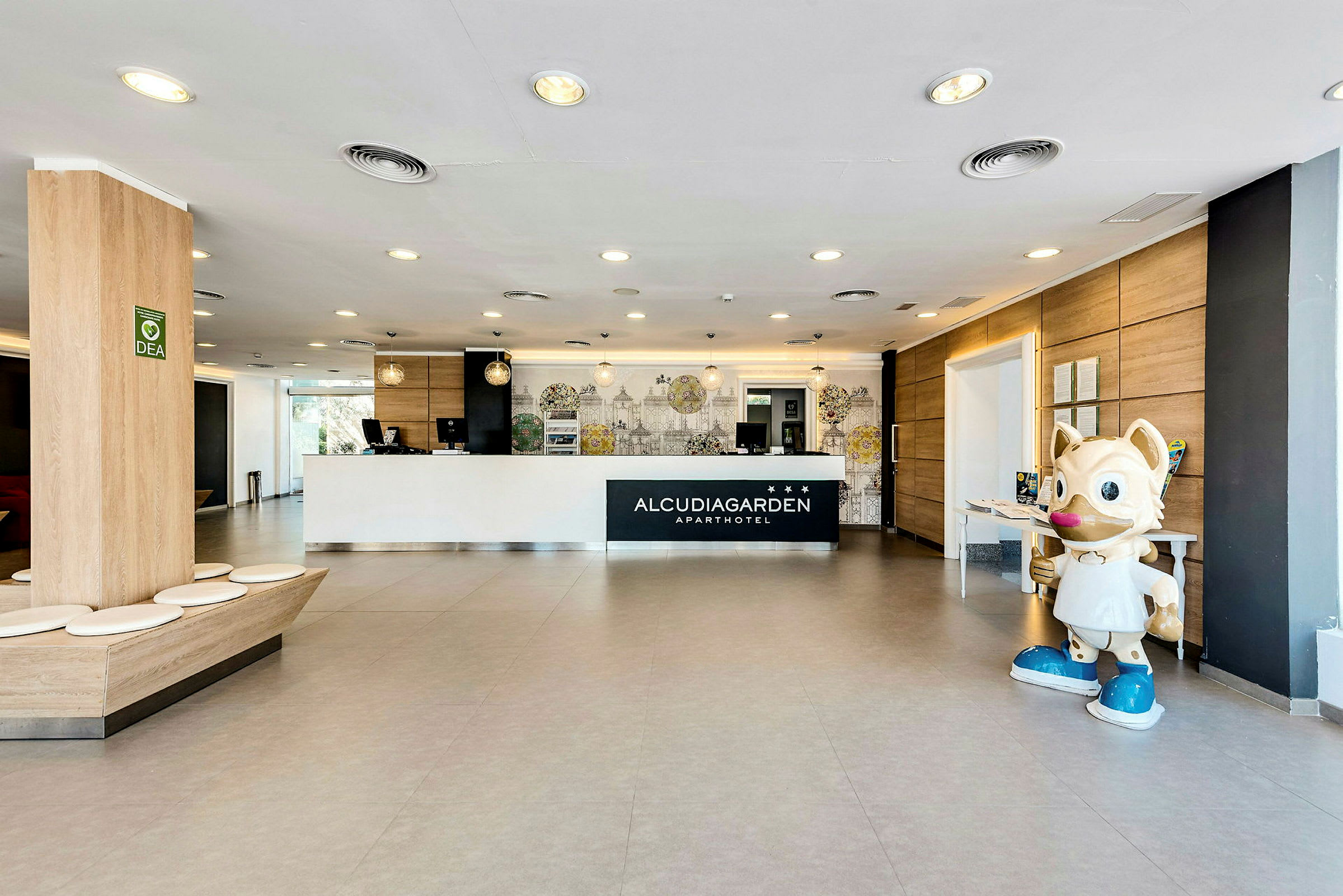 Receptionen på Alcudia Garden med en stor katteagtig statue til højre. (AI-genereret tekst)