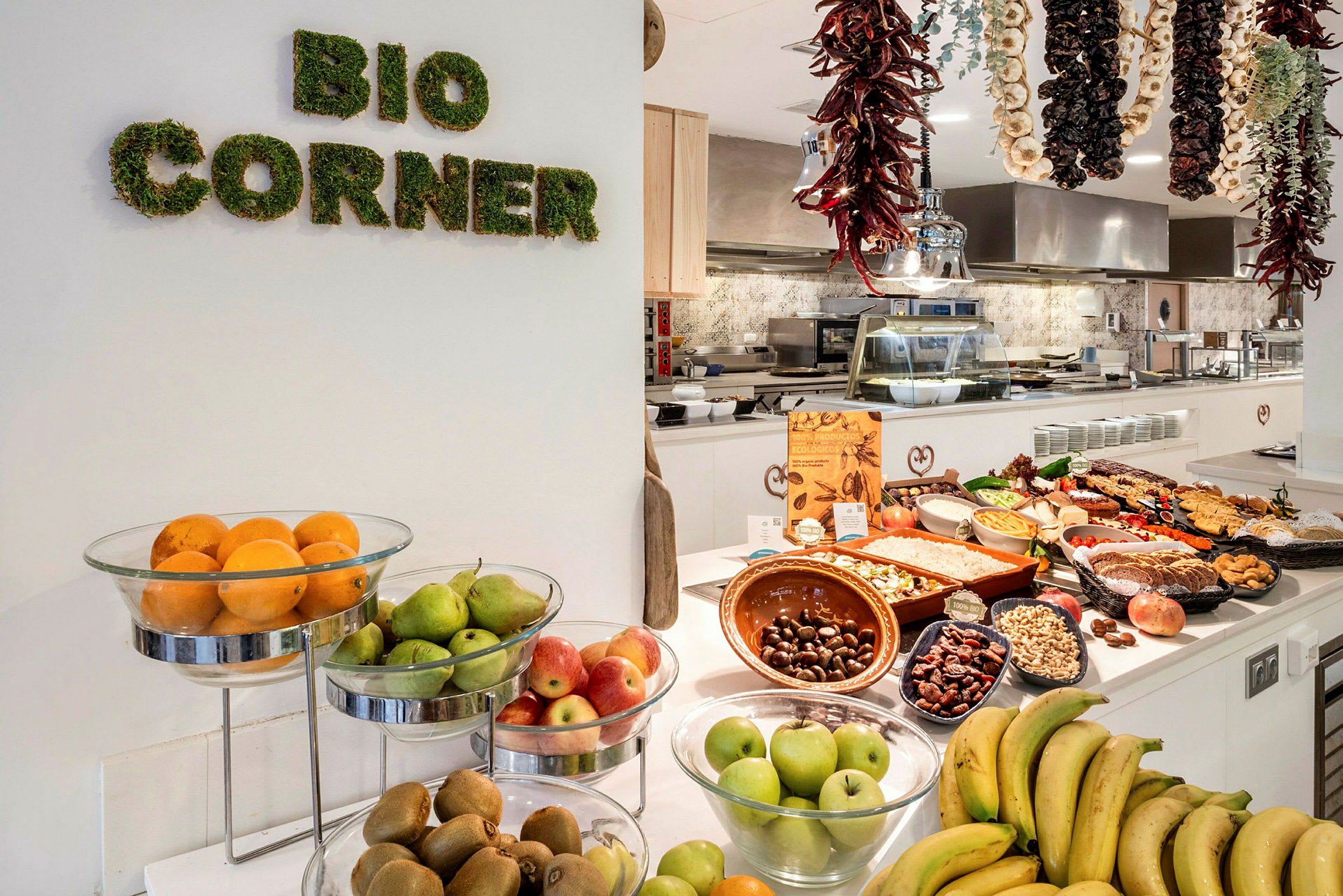 Frugt og madvarer på et bord i et køkkenområde med skiltet 'Bio Corner'. (AI-genereret tekst)
