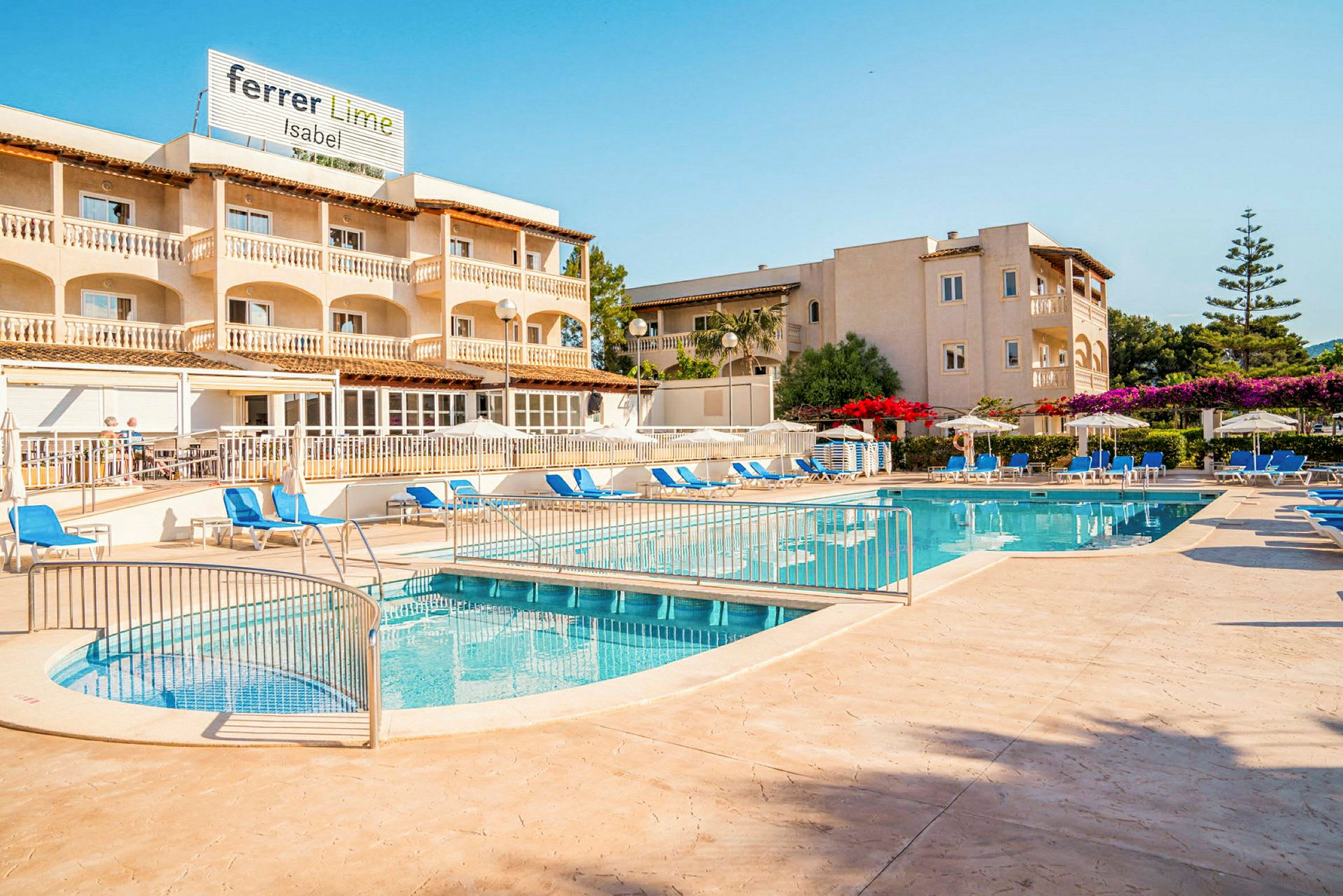 En udendørs pool med solsenge og parasoller foran et hotel. (AI-genereret tekst)