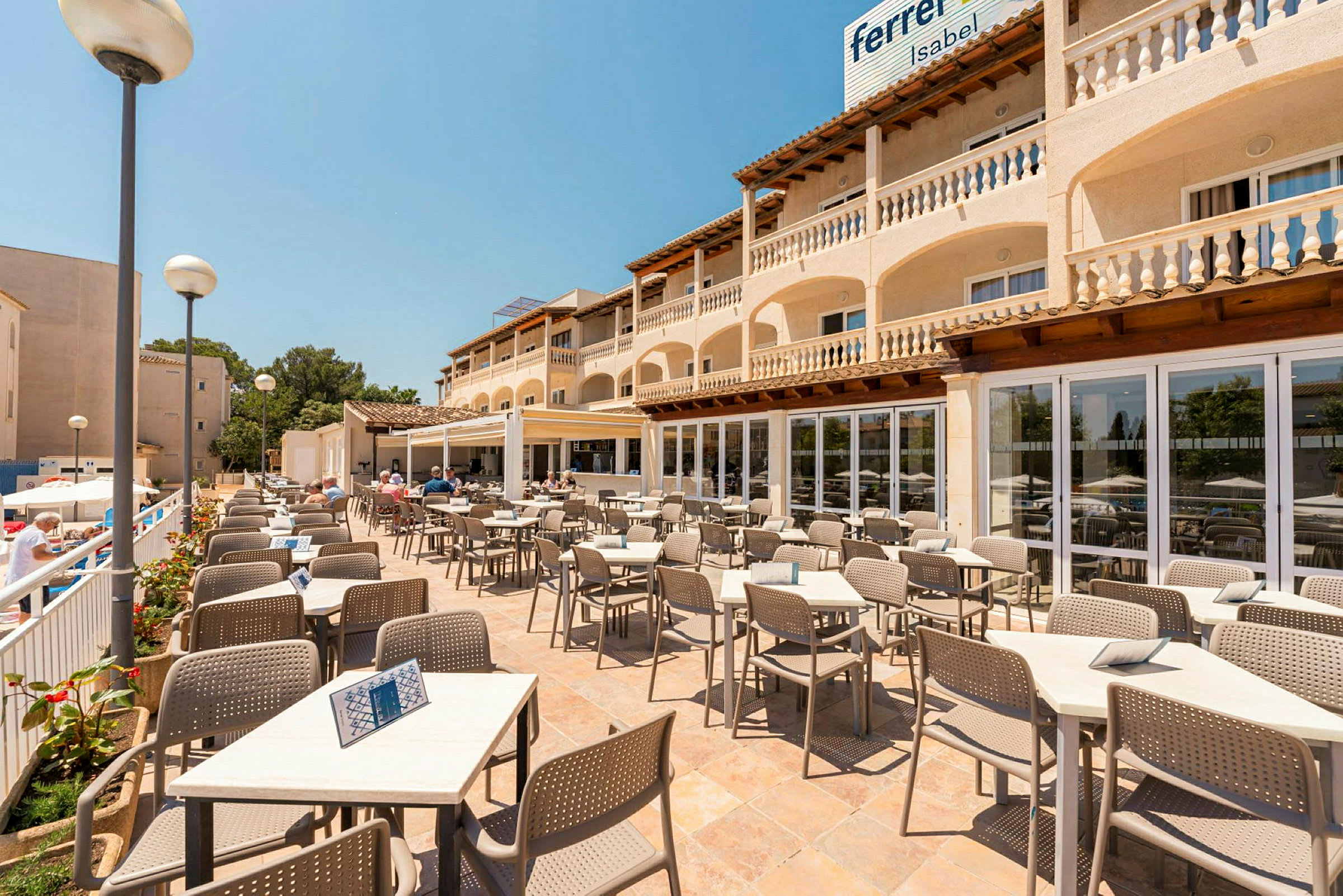 Terrasserestaurant med borde og stole, omgivet af en bygning med altaner. (AI-genereret tekst)